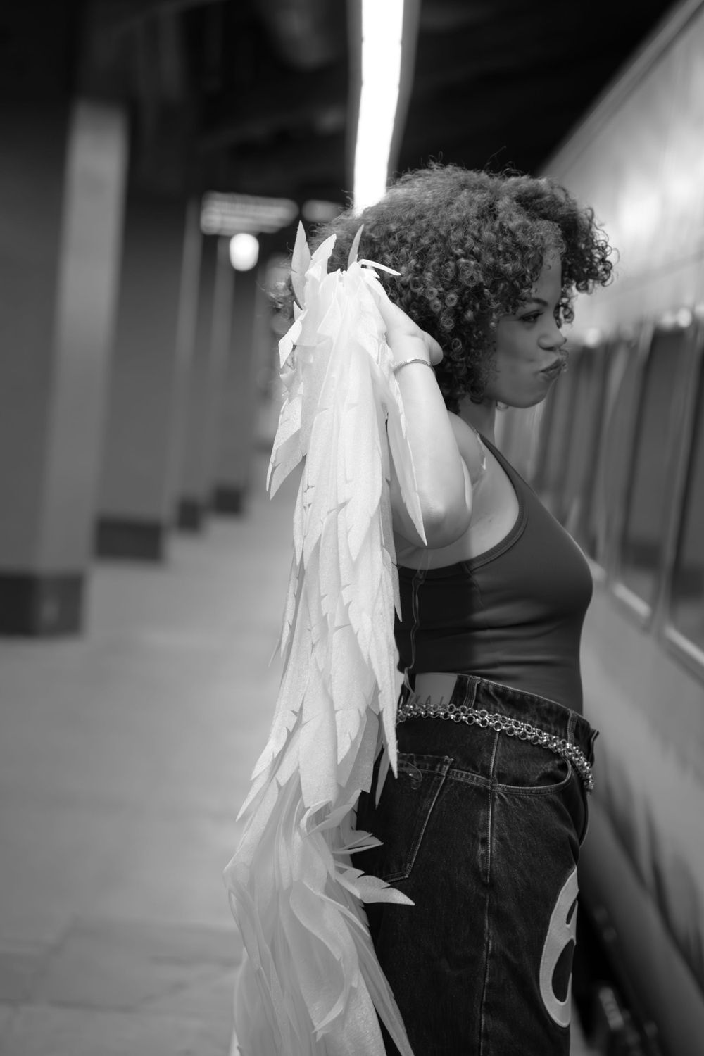Side view of someone wearing white angel wings in an industrial hallway.