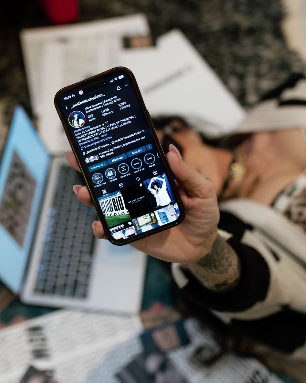 Hand holding smartphone displaying dark mode social media interface.