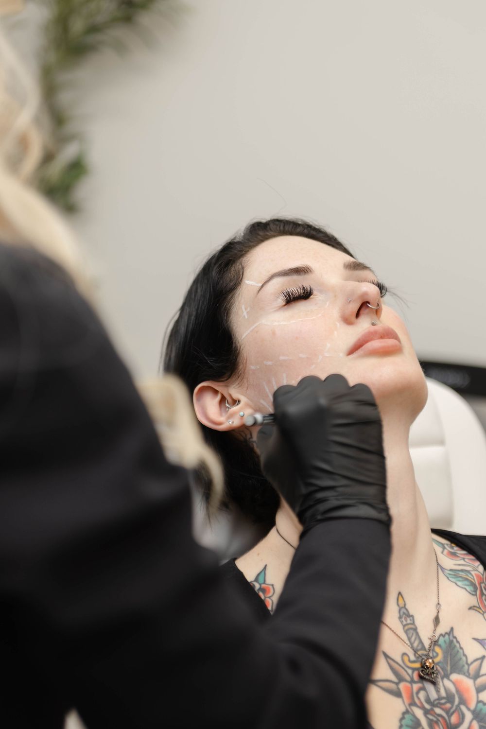 Close-up beauty treatment session showing hands wearing black gloves.