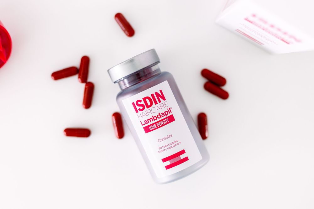 Medical or beauty product bottles arranged with red capsules on white background.