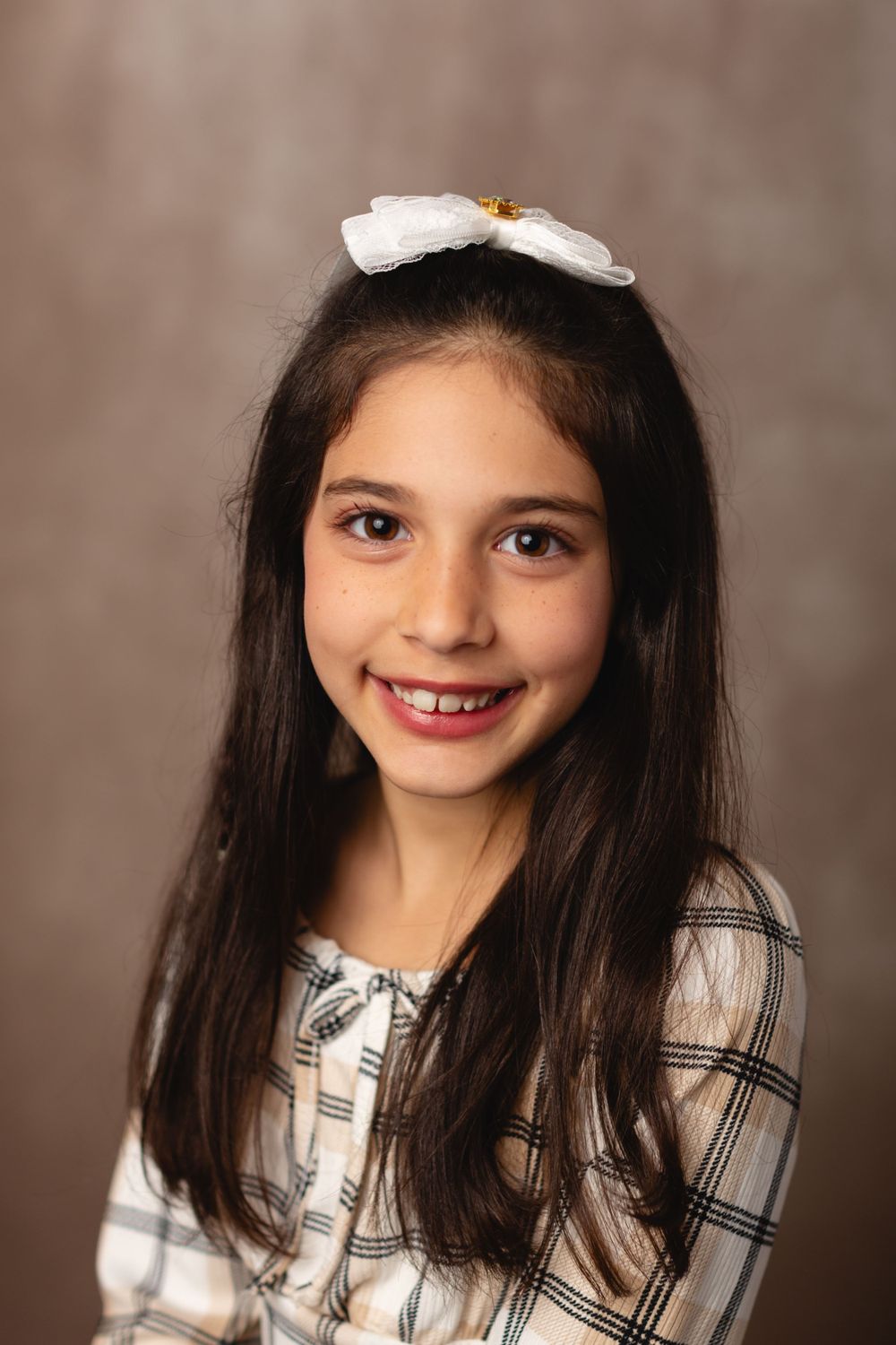 Homeschool child in casual outfit, smiling for a simple school portrait on a beige background