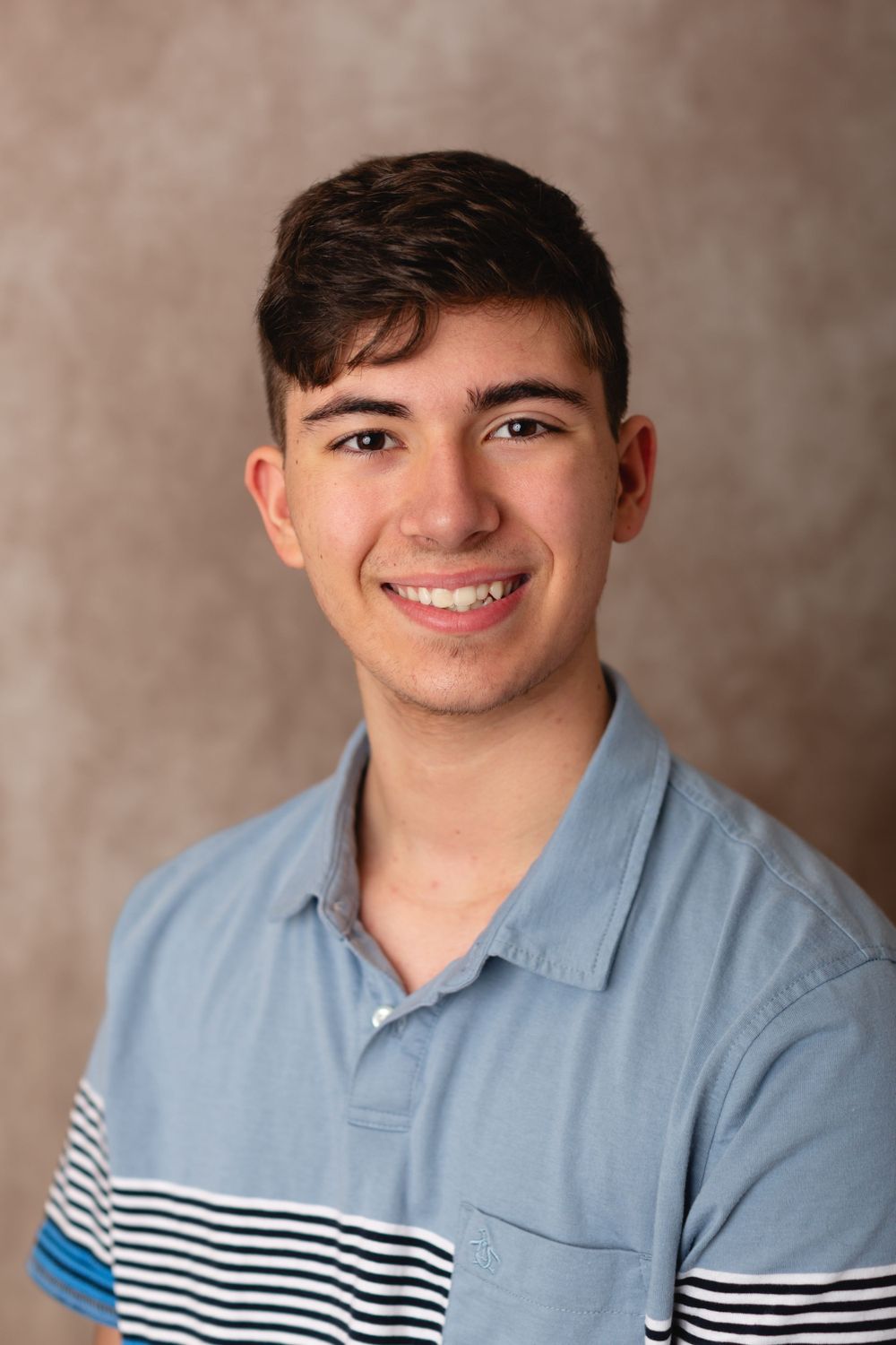 Homeschool teen in casual outfit, smiling for a simple school portrait on a beige background