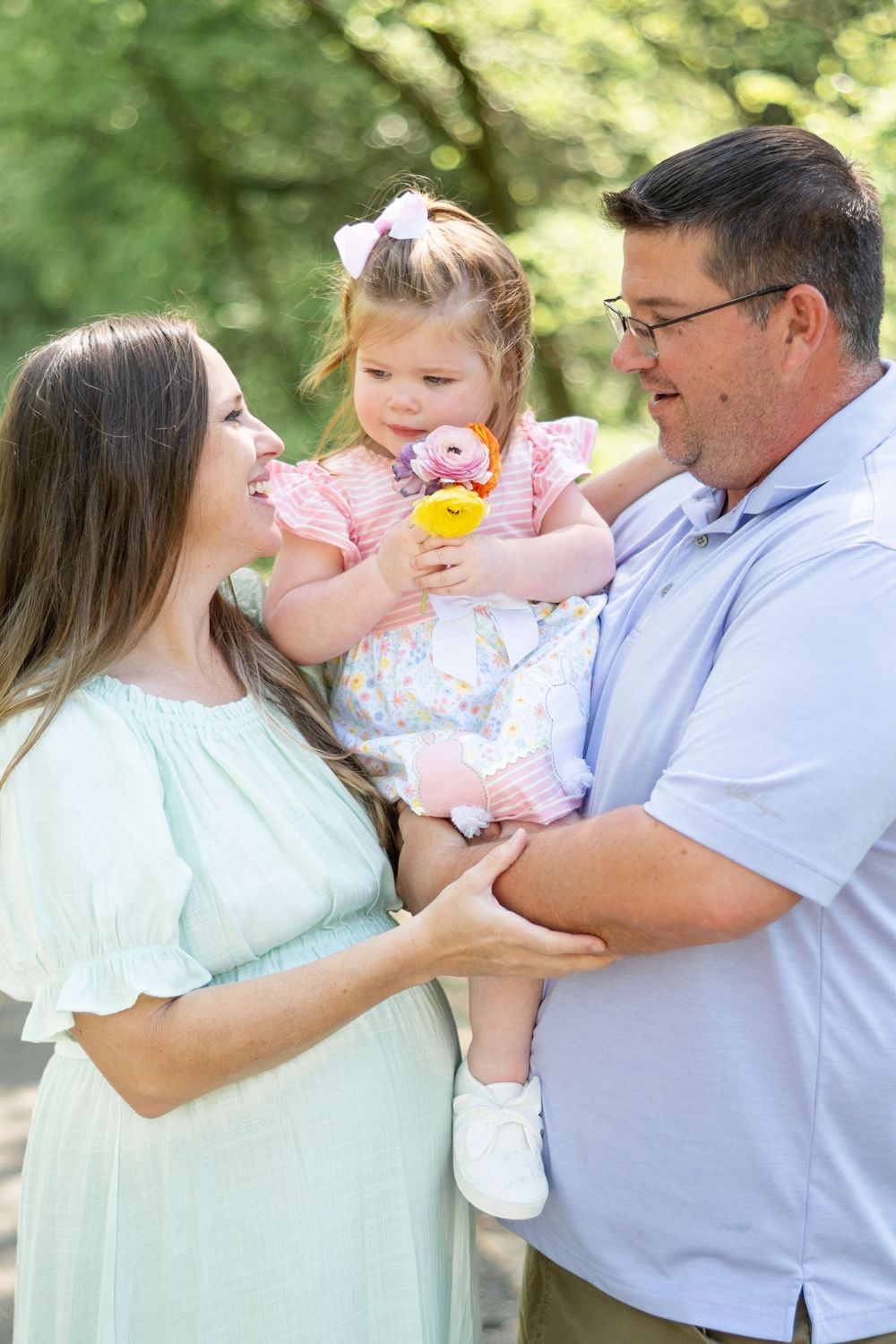 Family of three sharing a joyful moment together outdoors in spring attire.