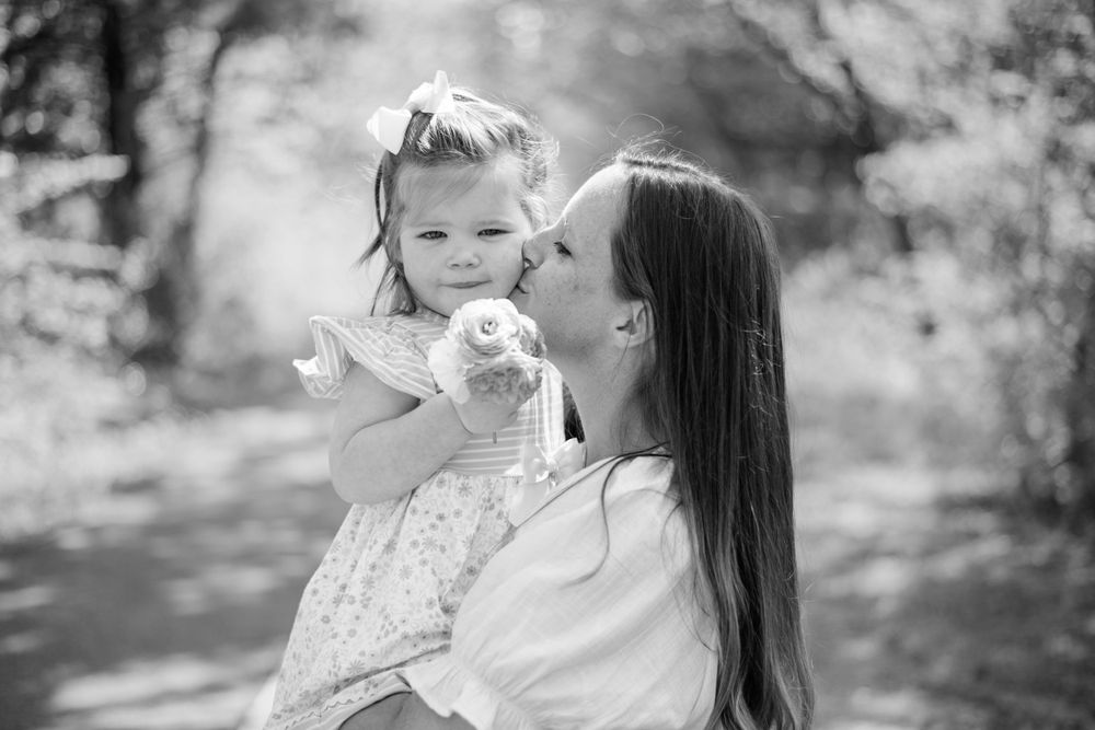 An intimate black and white moment between parent and child sharing affection in a natural setting.