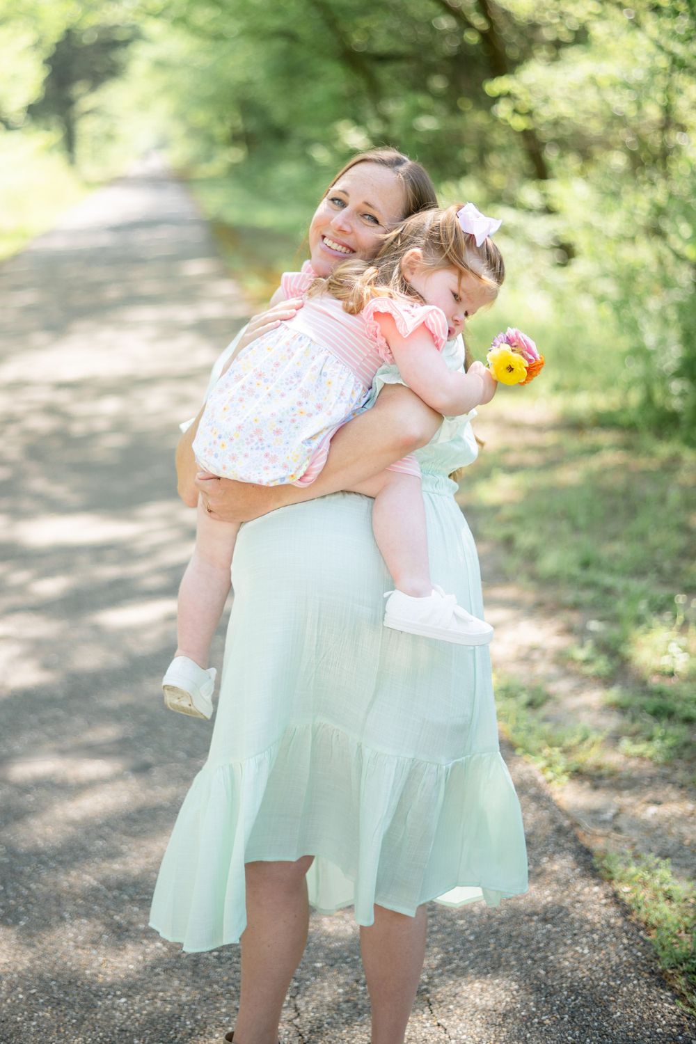 Two figures share a joyful moment while playing on a sunlit forest path in spring.
