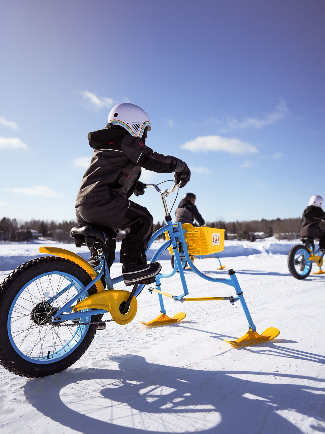 Action shots of a snow bike with yellow skis being ridden across a snowy field.
