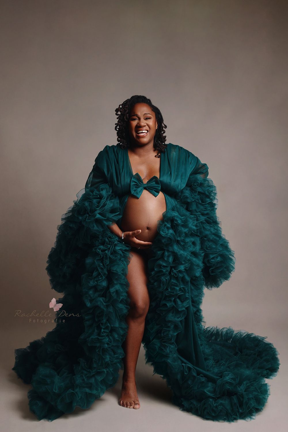 Glamorous portrait featuring a luxurious emerald green tulle robe with dramatic ruffles against a neutral studio backdrop.