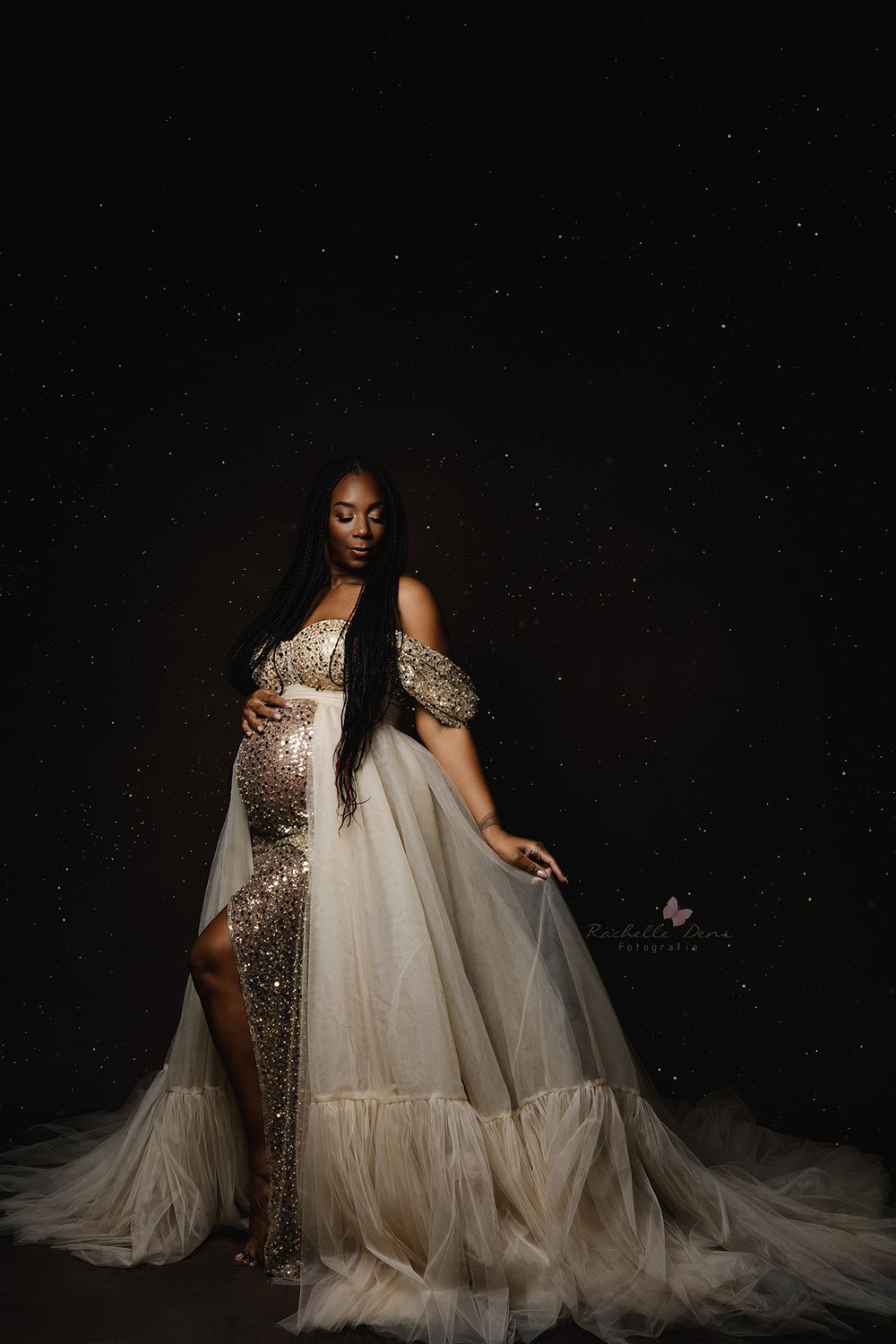 A glamorous evening gown in sparkling gold sequins and flowing white tulle shot against a dramatic black background.