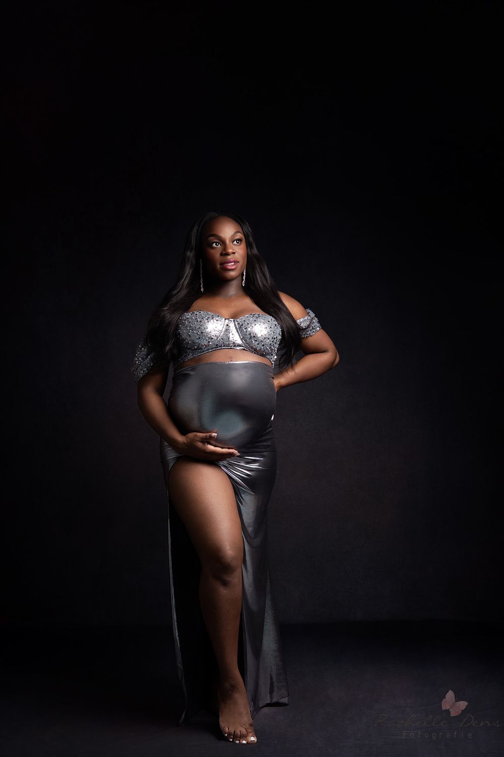 Dramatic studio portrait featuring silver evening wear with lace details against dark background.