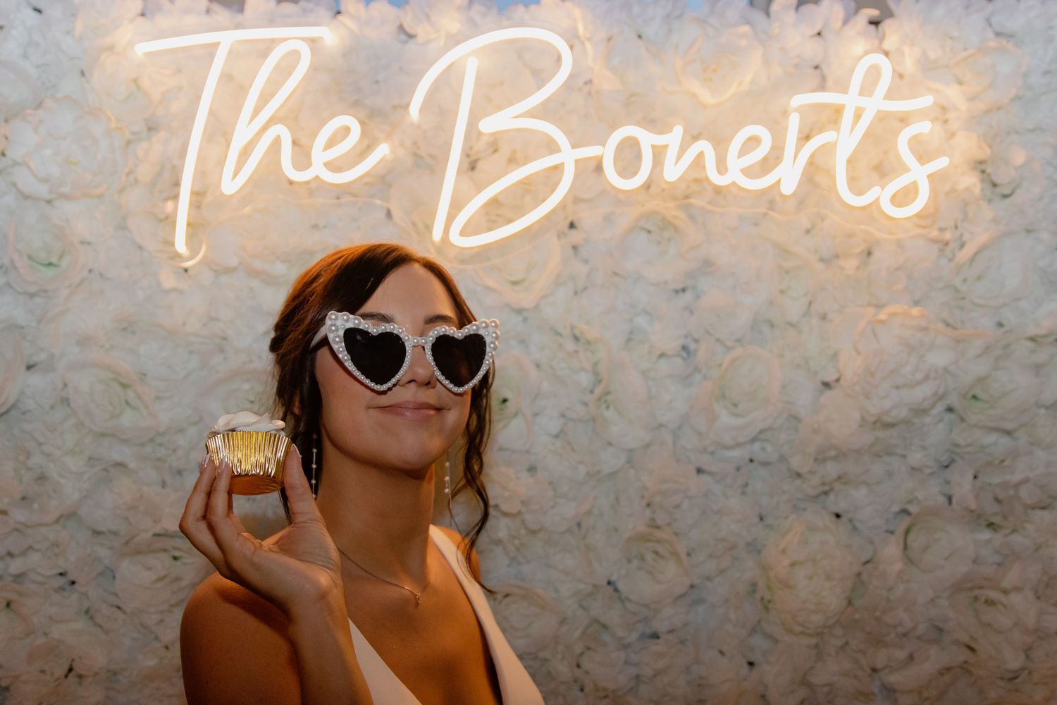 Illuminated neon sign against textured wall at wedding reception.