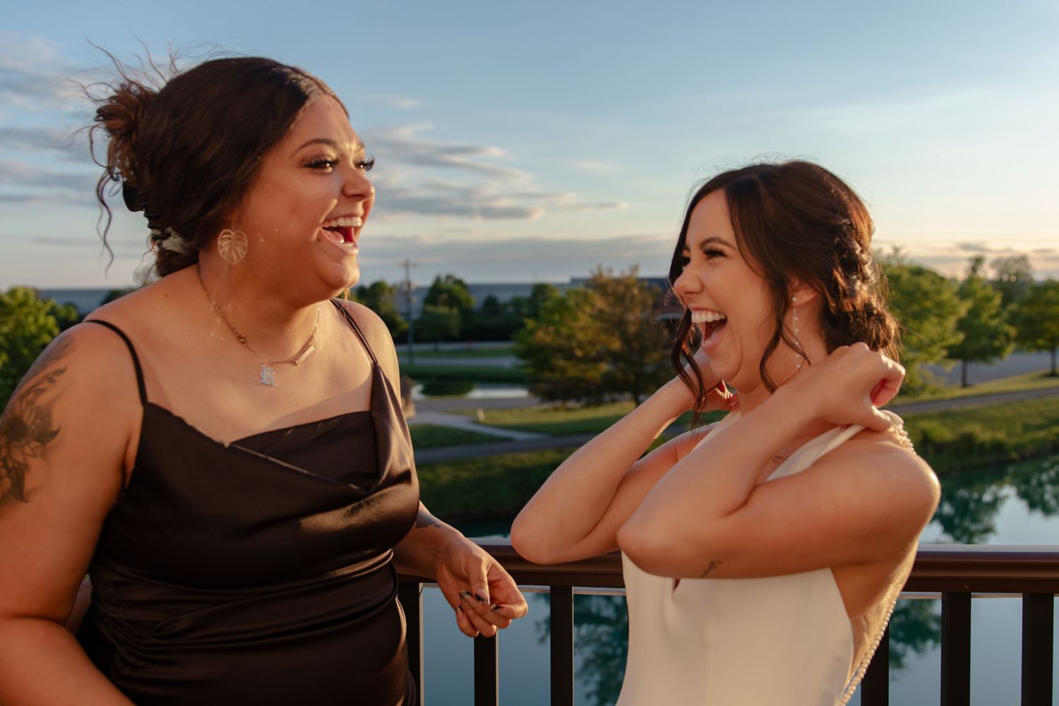 bride with friend celebrate joyfully during outdoor wedding photos at sunset.