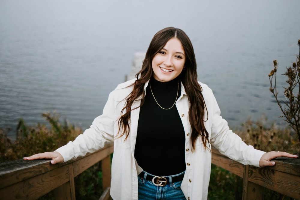 A casual portrait session by the water featuring someone in layered fall clothing.