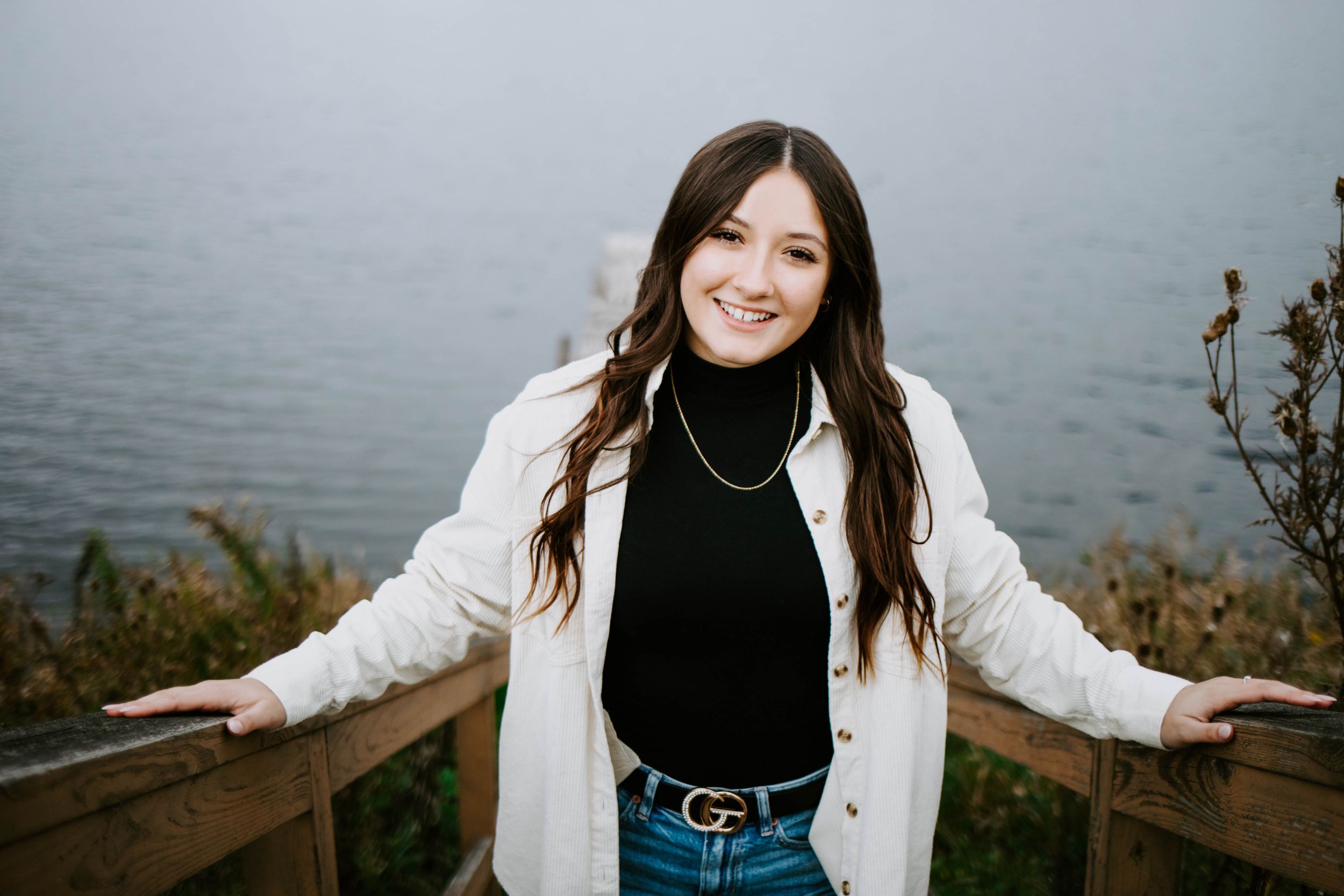 A casual portrait session by the water featuring someone in layered fall clothing.