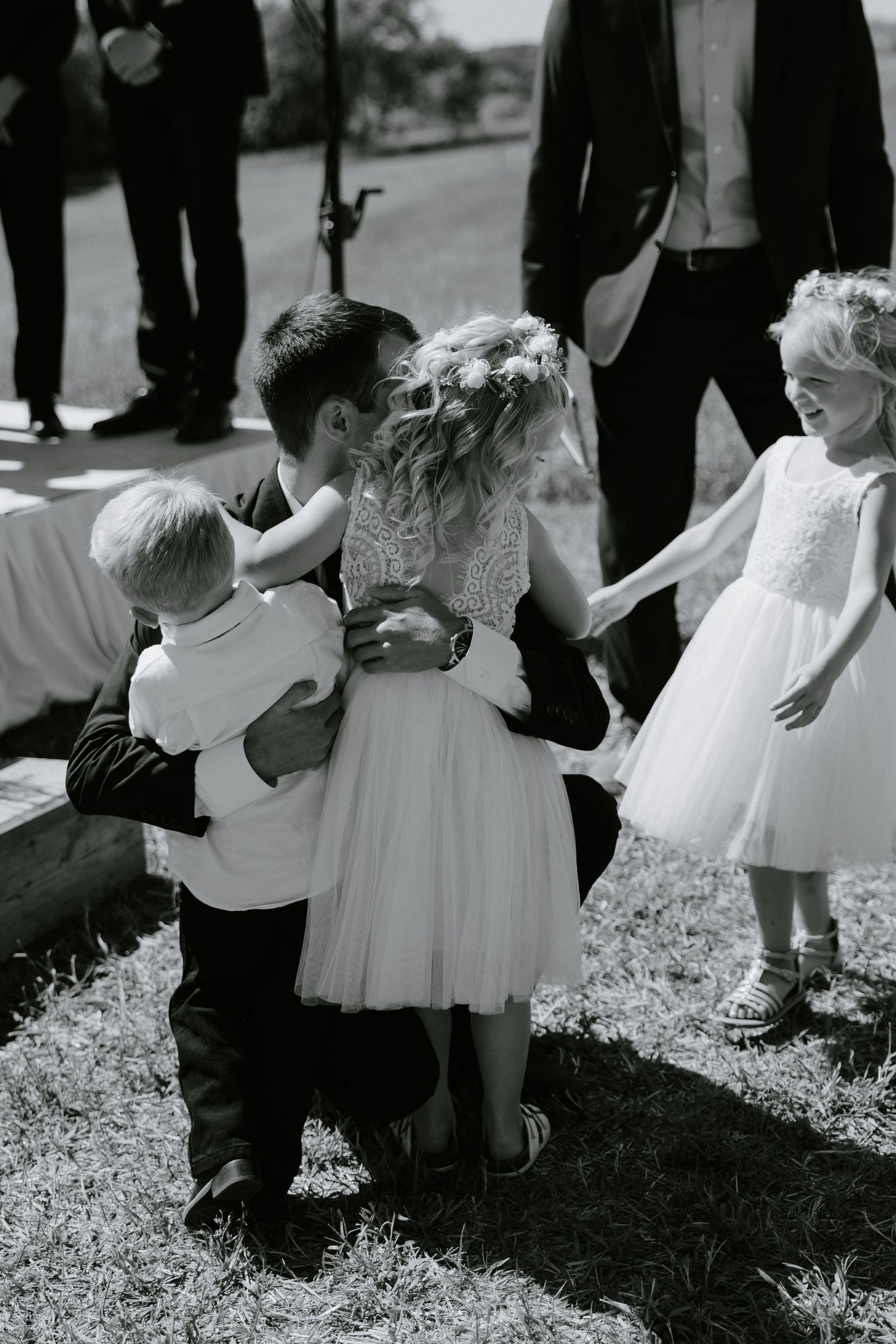 Black and white photo of children in formal attire playing and dancing together at an outdoor event.