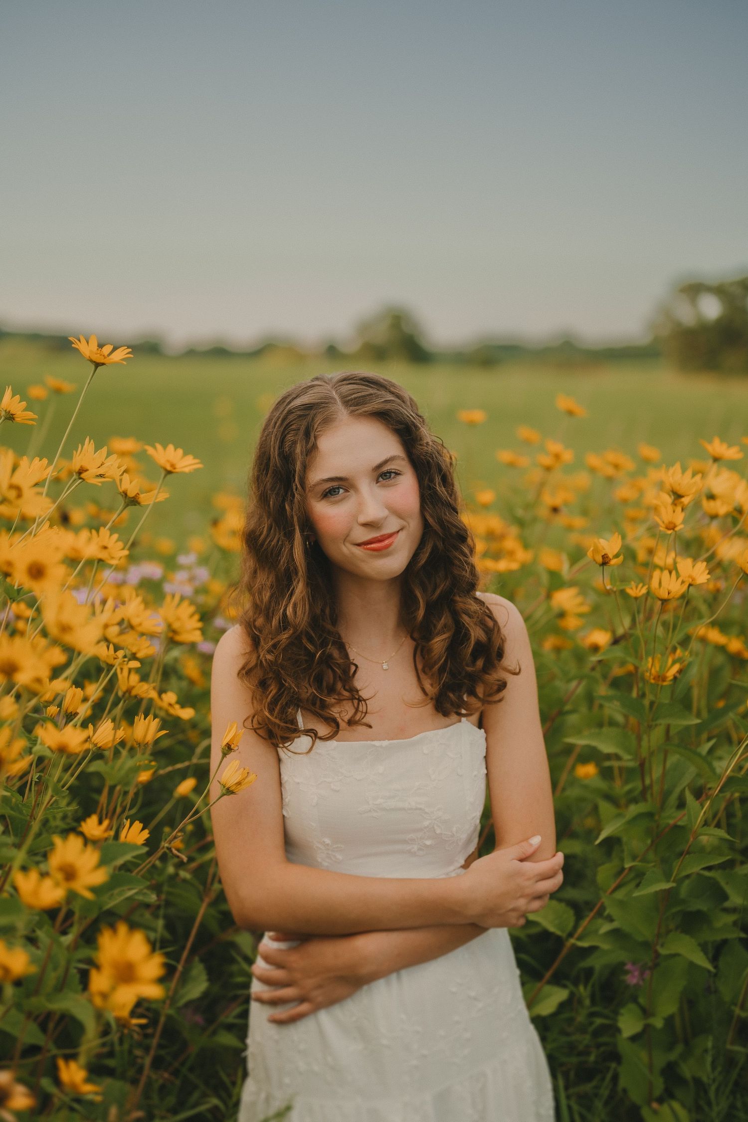 White dress in yellow wildflower field during golden hour with soft natural lighting and dreamy summer atmosphere.