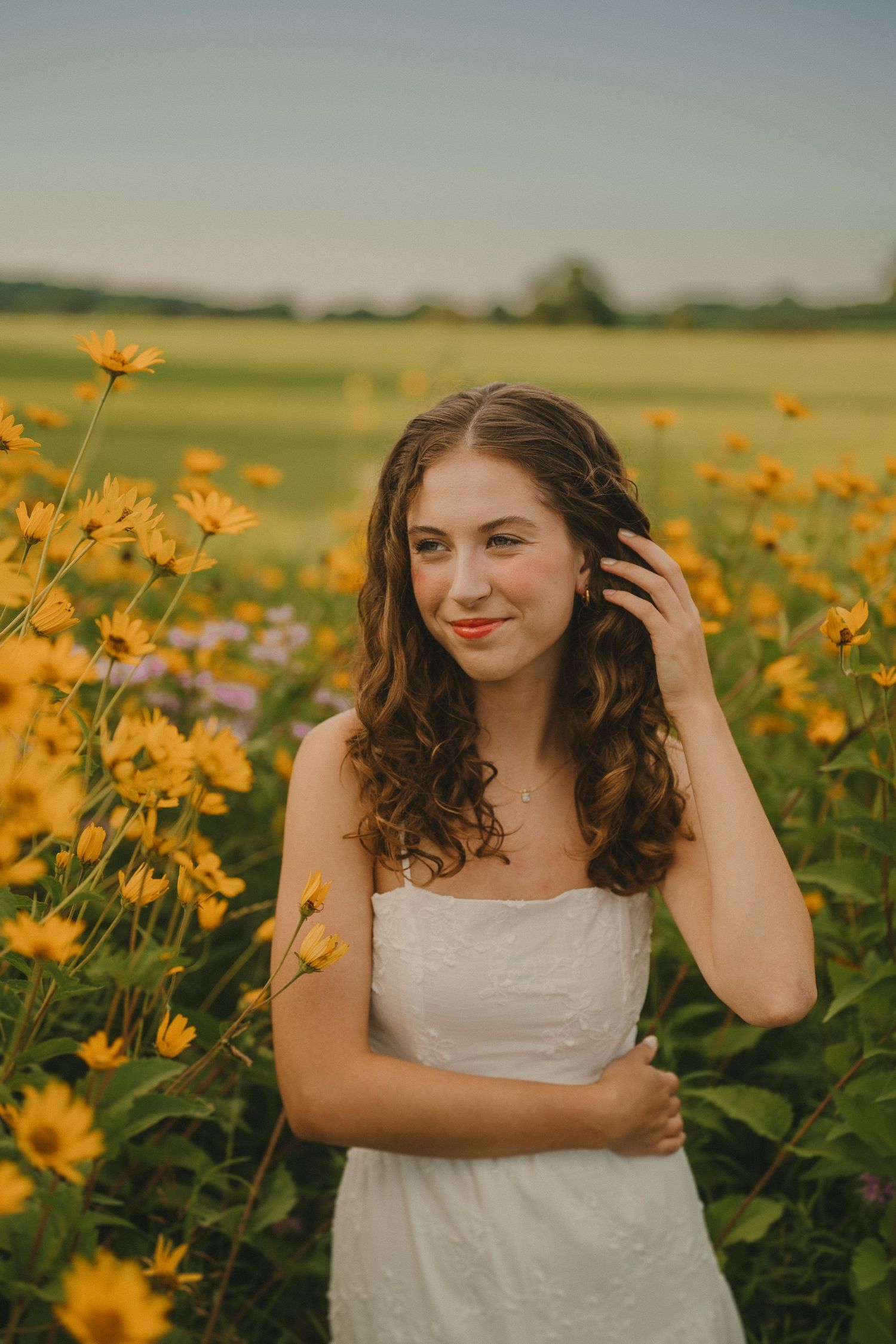 A white dress contrasts beautifully with vibrant yellow wildflowers in a summer field at golden hour.