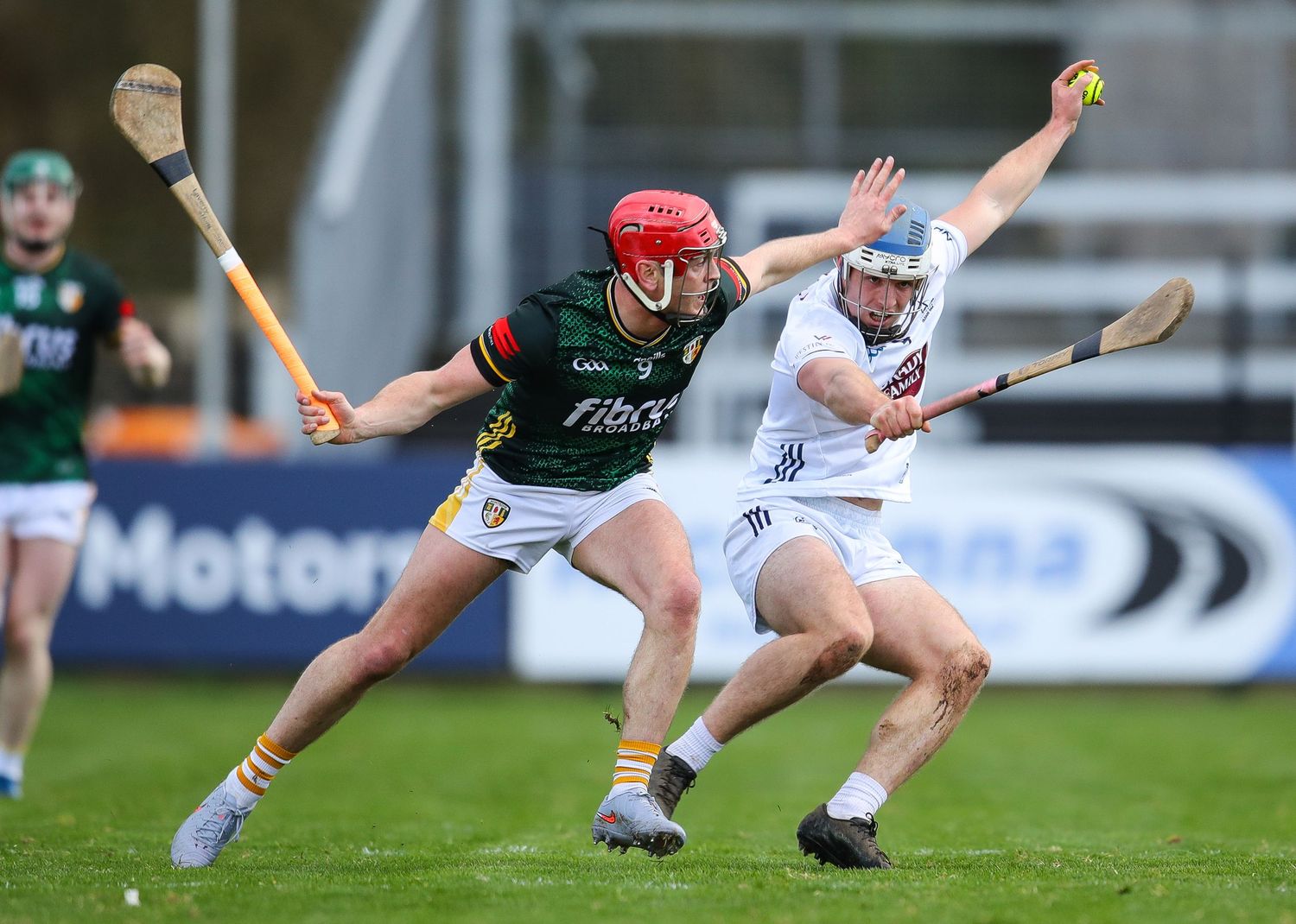 Hurling players compete for possession during an intense match on a grass field.