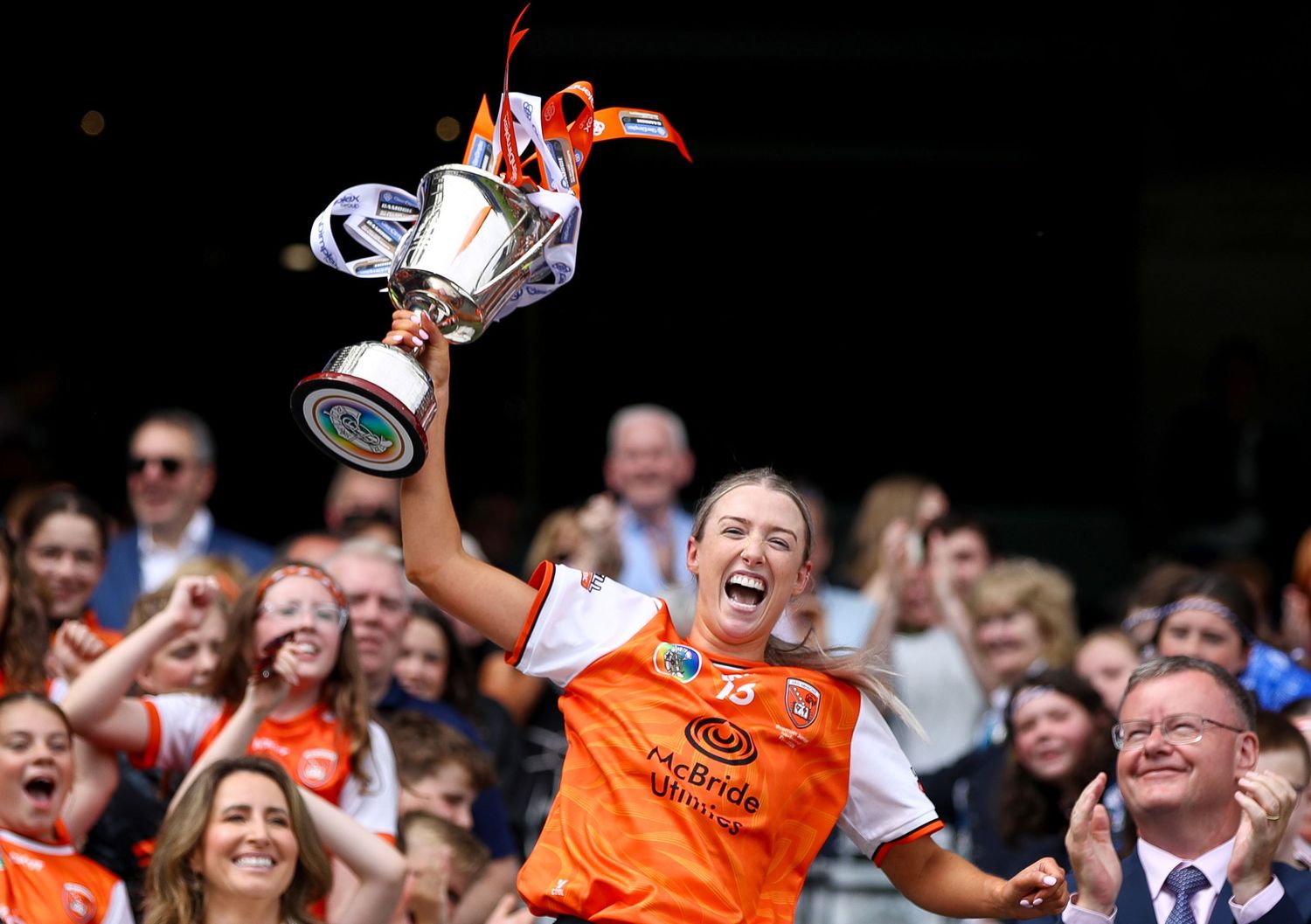 Armagh player lifts trophy celebrating GAA championship victory before cheering crowd at Croke Park.