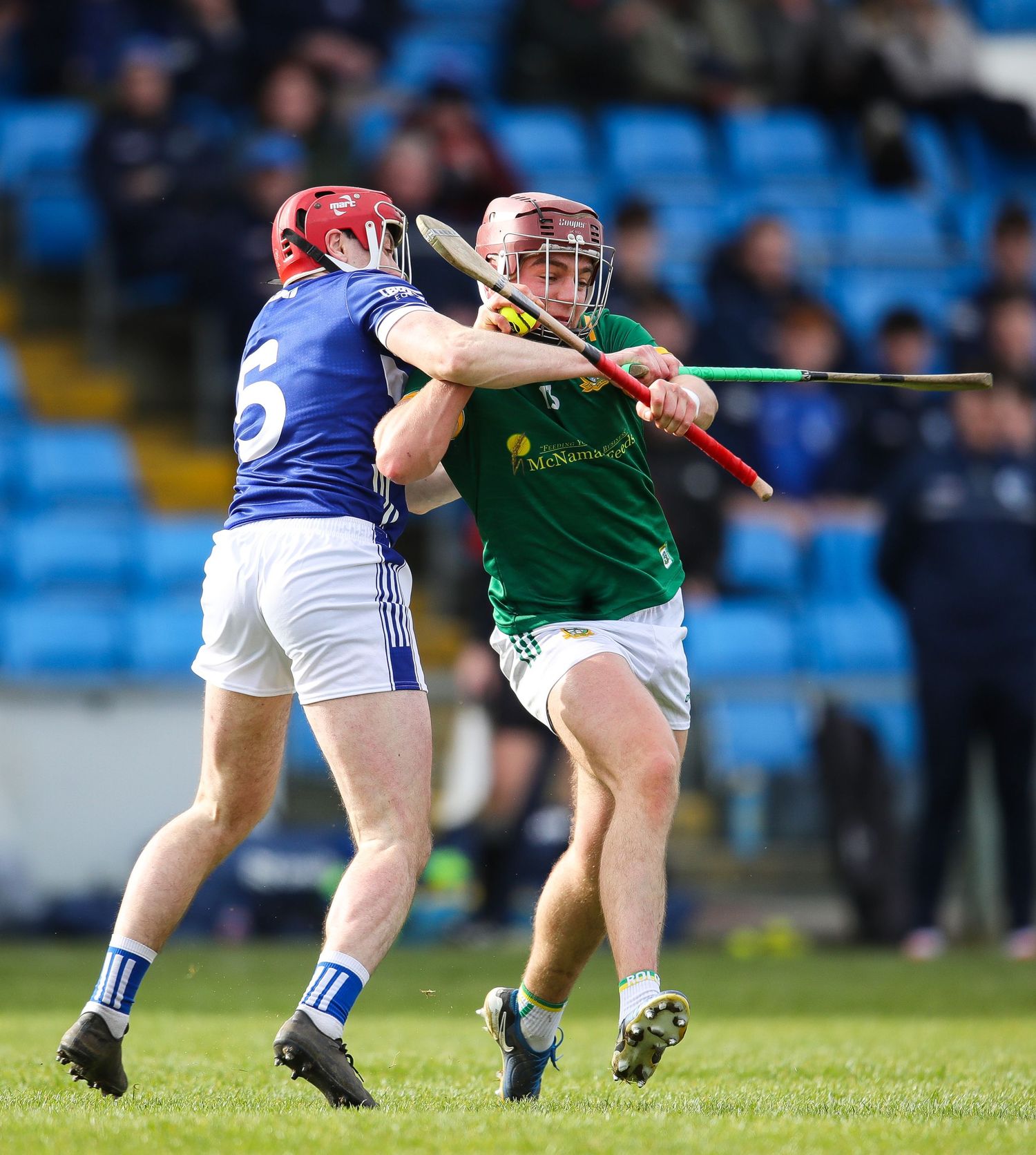 Close-up action shot of hurling players' legs and hurleys competing for possession during a match.