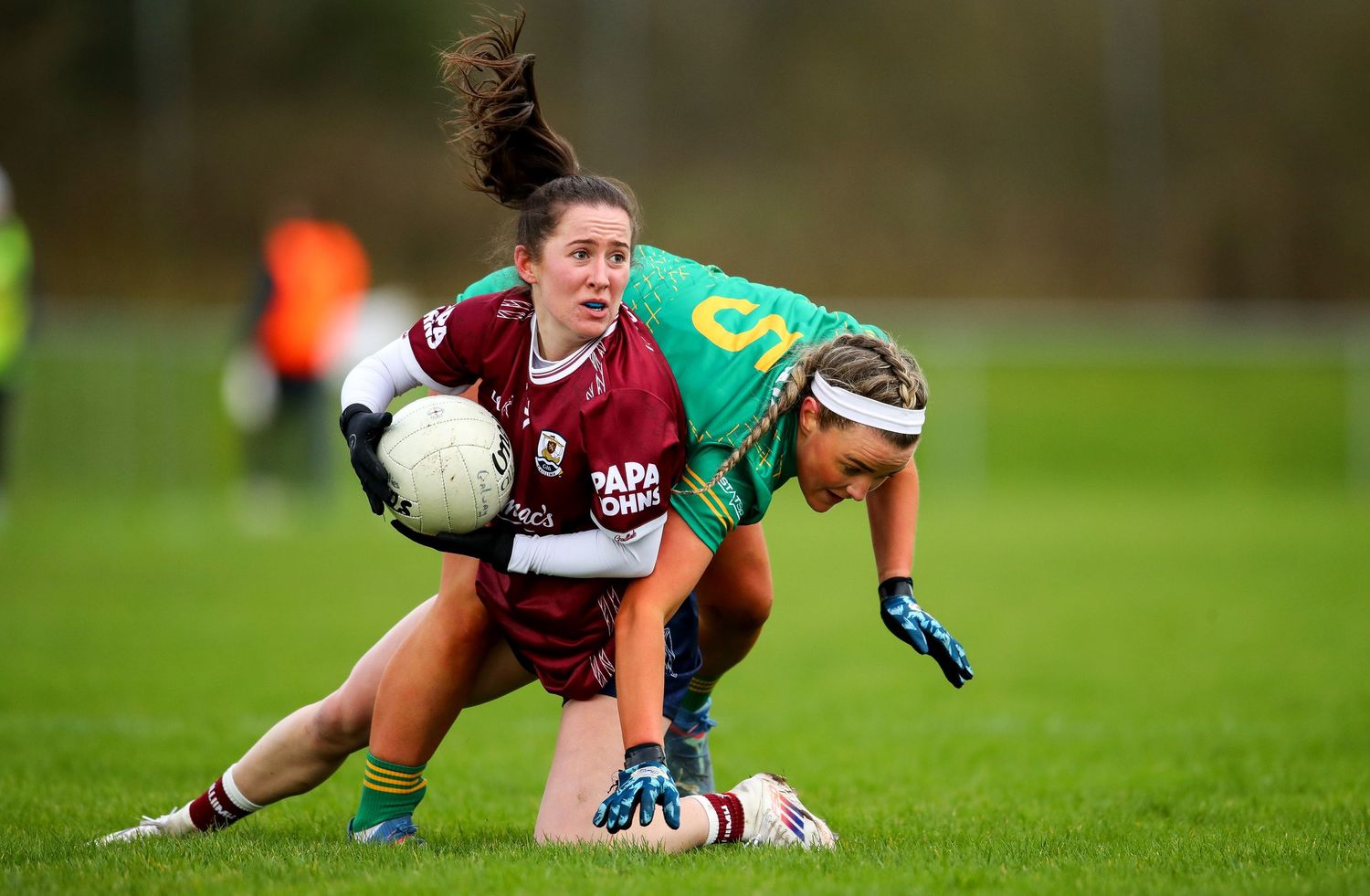 Rugby players making dramatic diving tackles on green sports field.