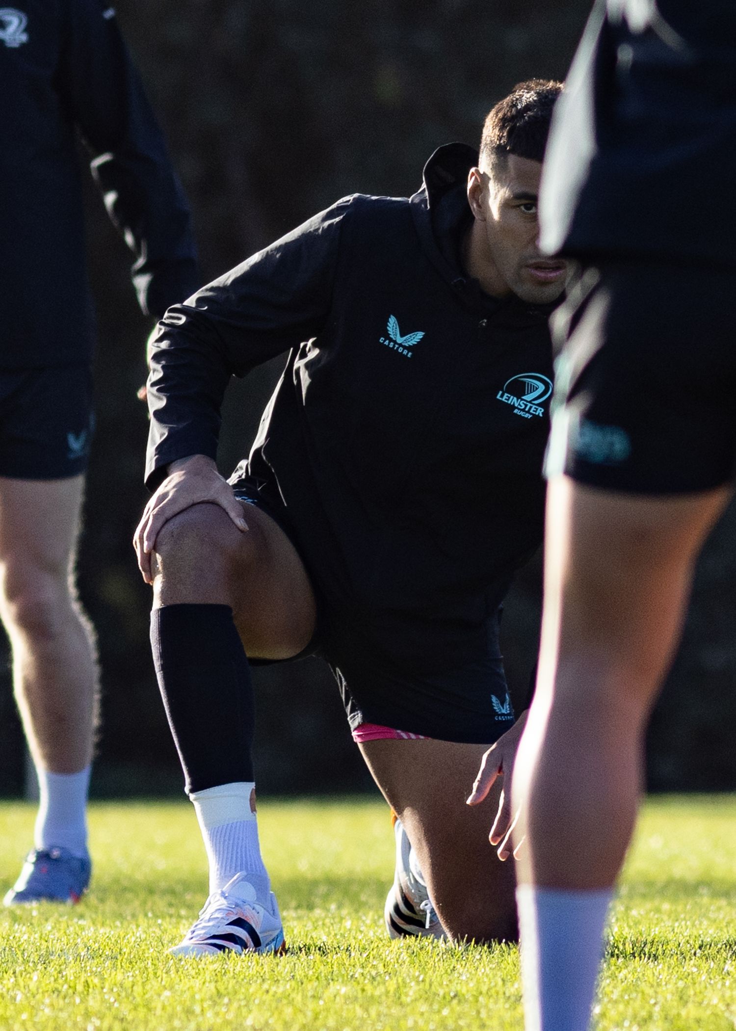 Close-up of rugby players' legs and cleats on grass during practice.