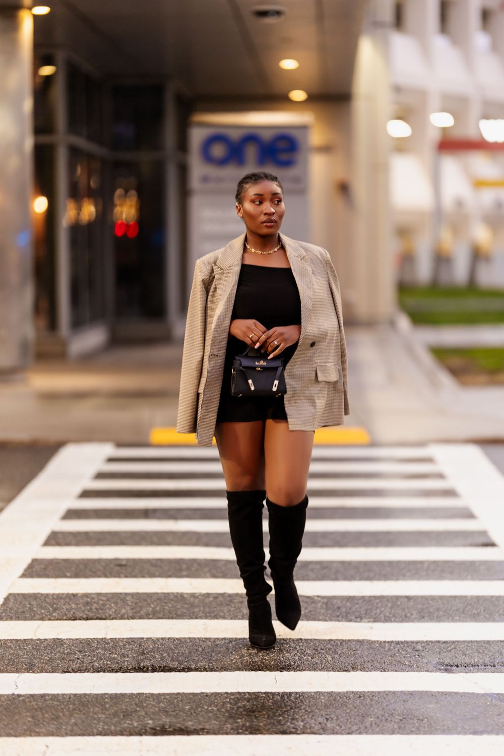 Fashion photo of someone walking across a zebra crossing in a blazer and boots.