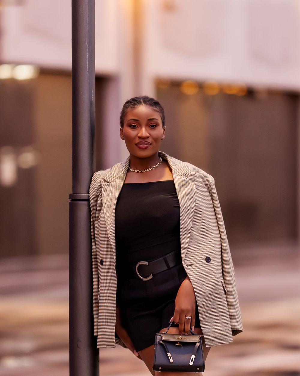 Stylish urban photoshoot featuring a beige blazer and black outfit against city backdrop.