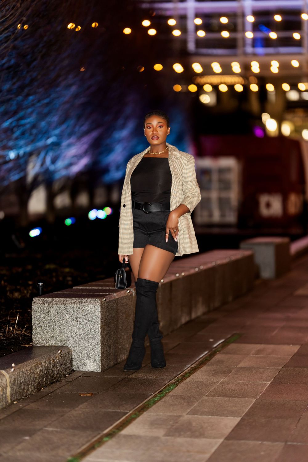 Evening fashion shoot along an illuminated walkway with bokeh lights in background.
