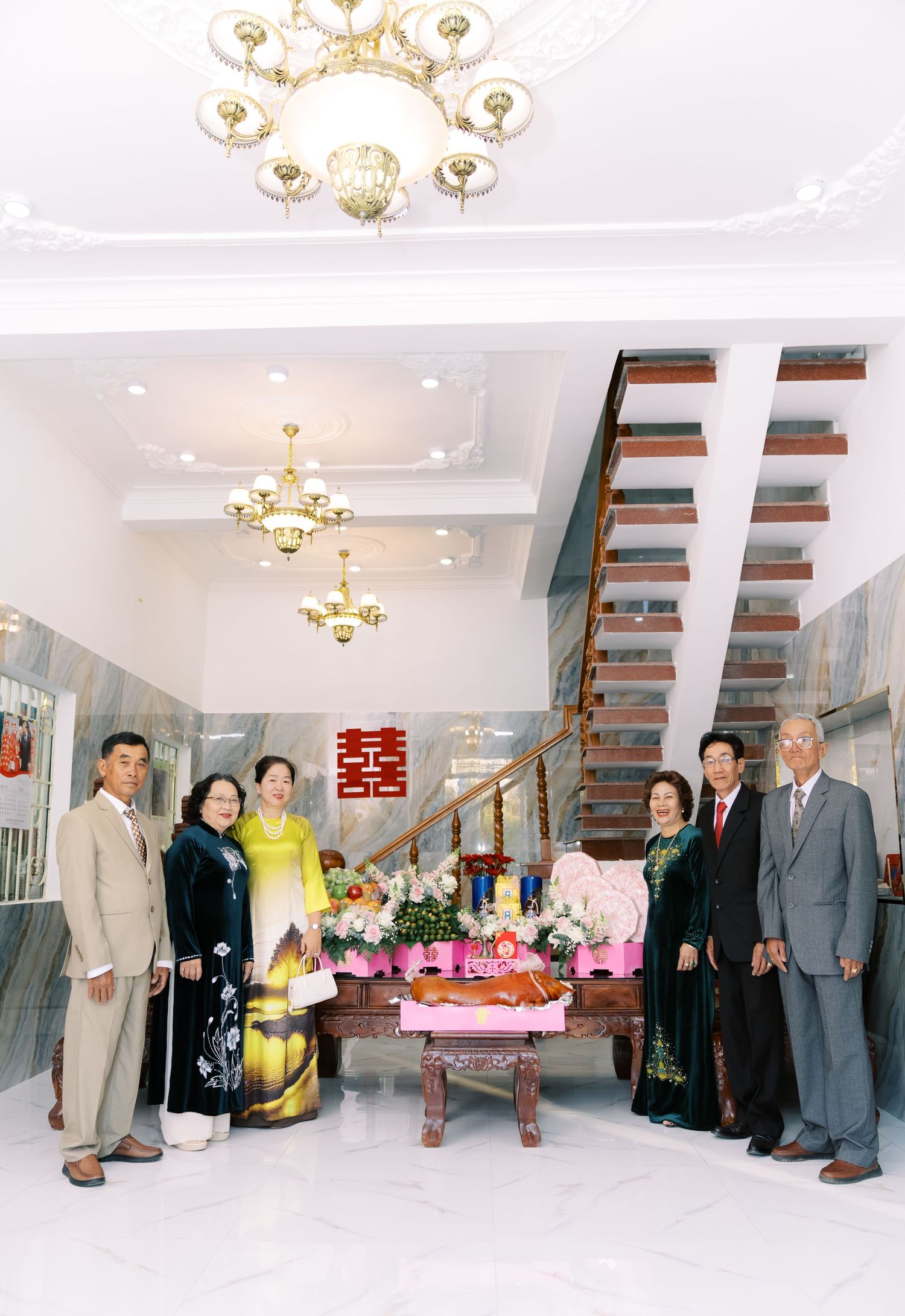 Interior scene with a luxury chandelier, modern floating staircase and group gathering around a decorative table.