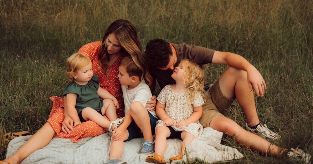 Candid family moment lounging together on blanket in grassy field. Virginia family photographer.