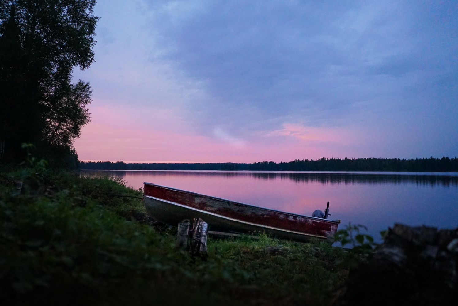 Panoramic sunset view over a tranquil lake with pink and purple sky.