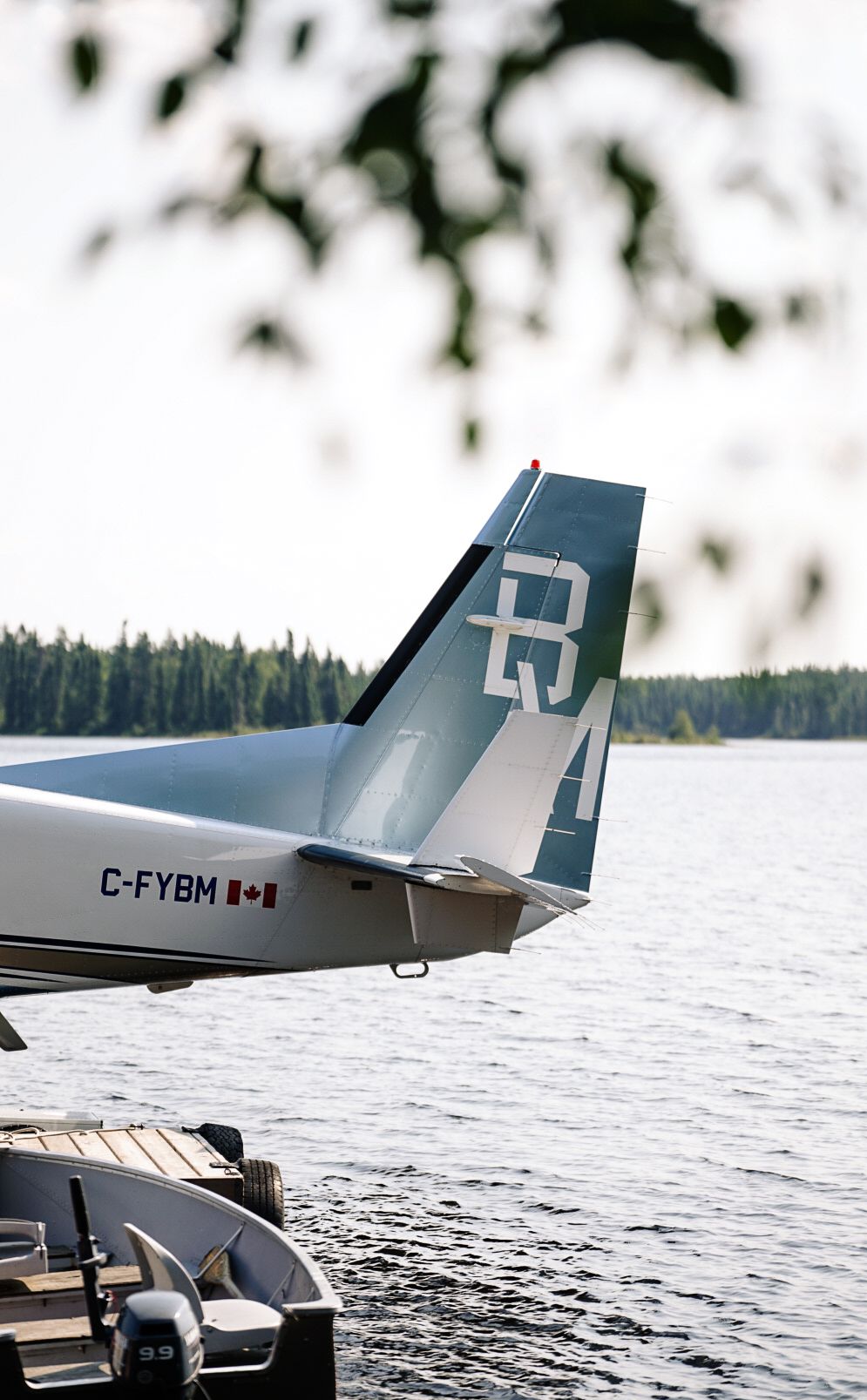 Seaplane tail sections with registration numbers visible on calm lake waters.