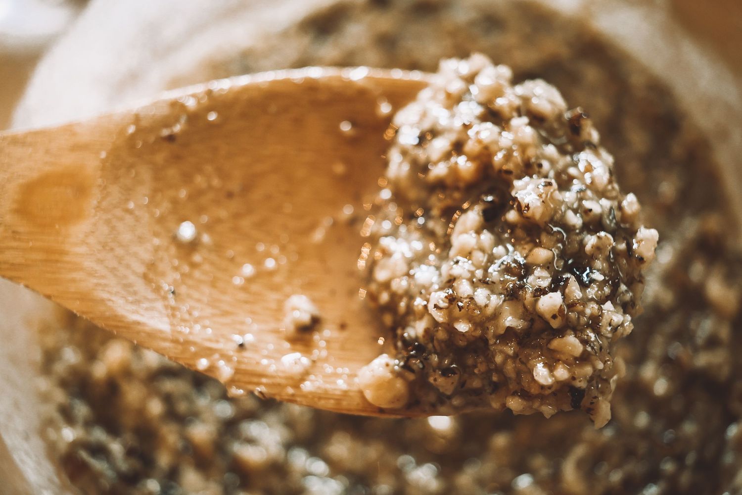 Wooden spoon scooping quinoa grains with shallow depth of field in macro photography.