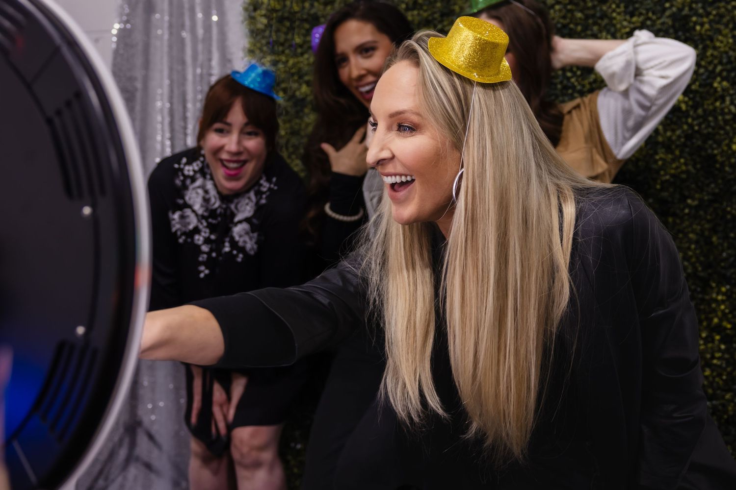 Group gathers around a commercial washing machine, with someone wearing a bright yellow bow smiling in the center.