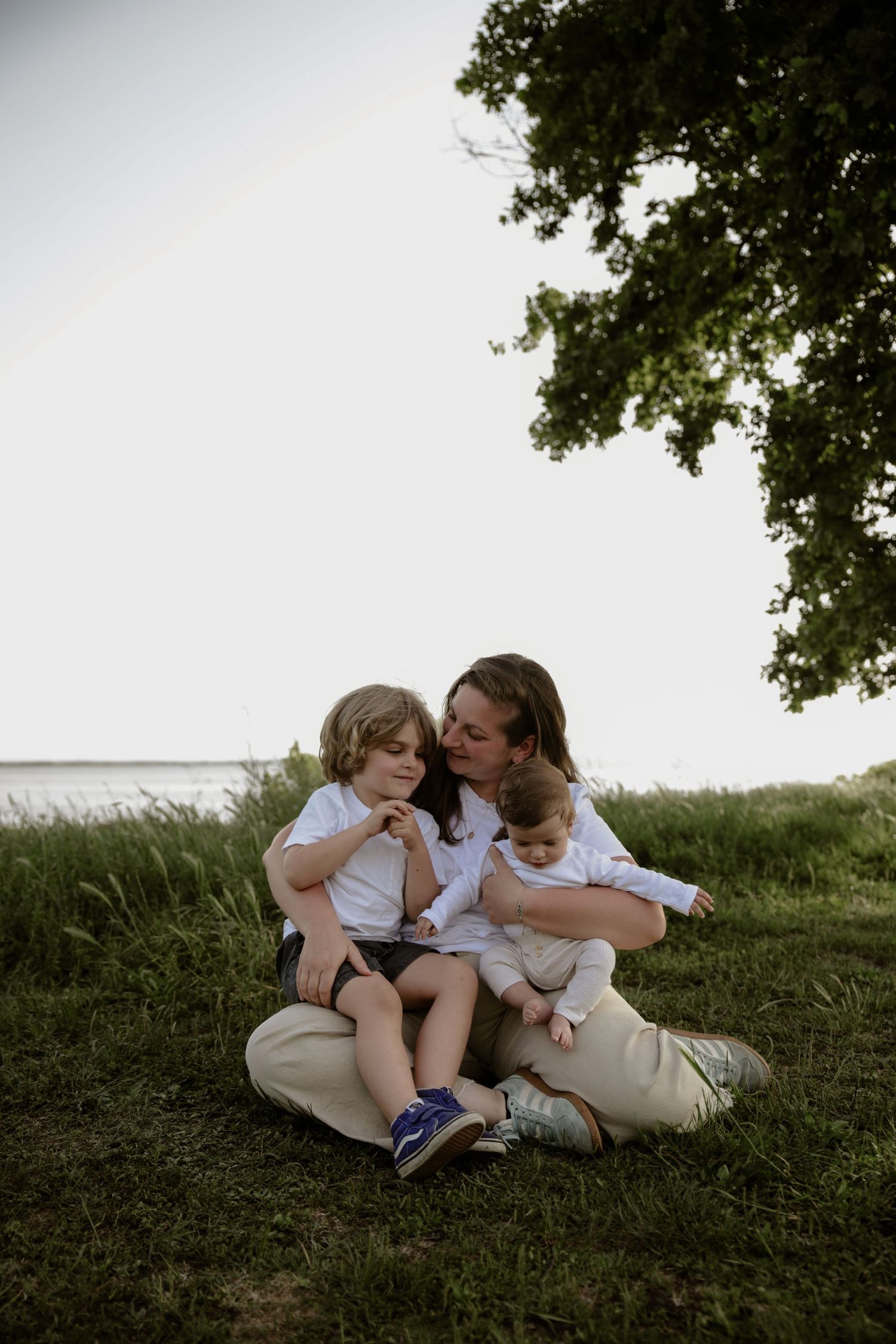 A couple sits together on a grassy hill during an intimate photo session on a summer afternoon.
