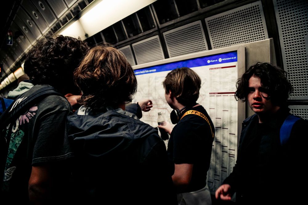 Group of people gathered in a subway station looking at transit information.