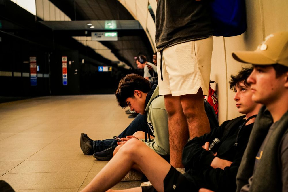 People sitting on the floor of a dimly lit subway station or tunnel.