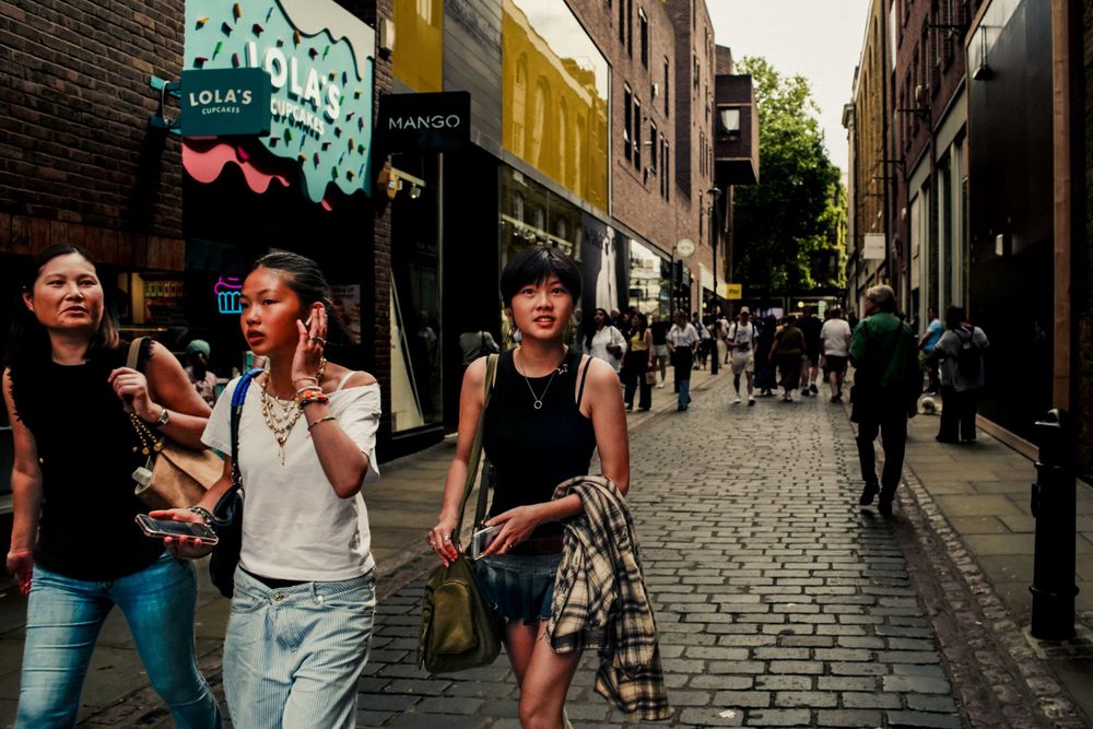 People walking down a cobblestone street lined with shops and businesses.