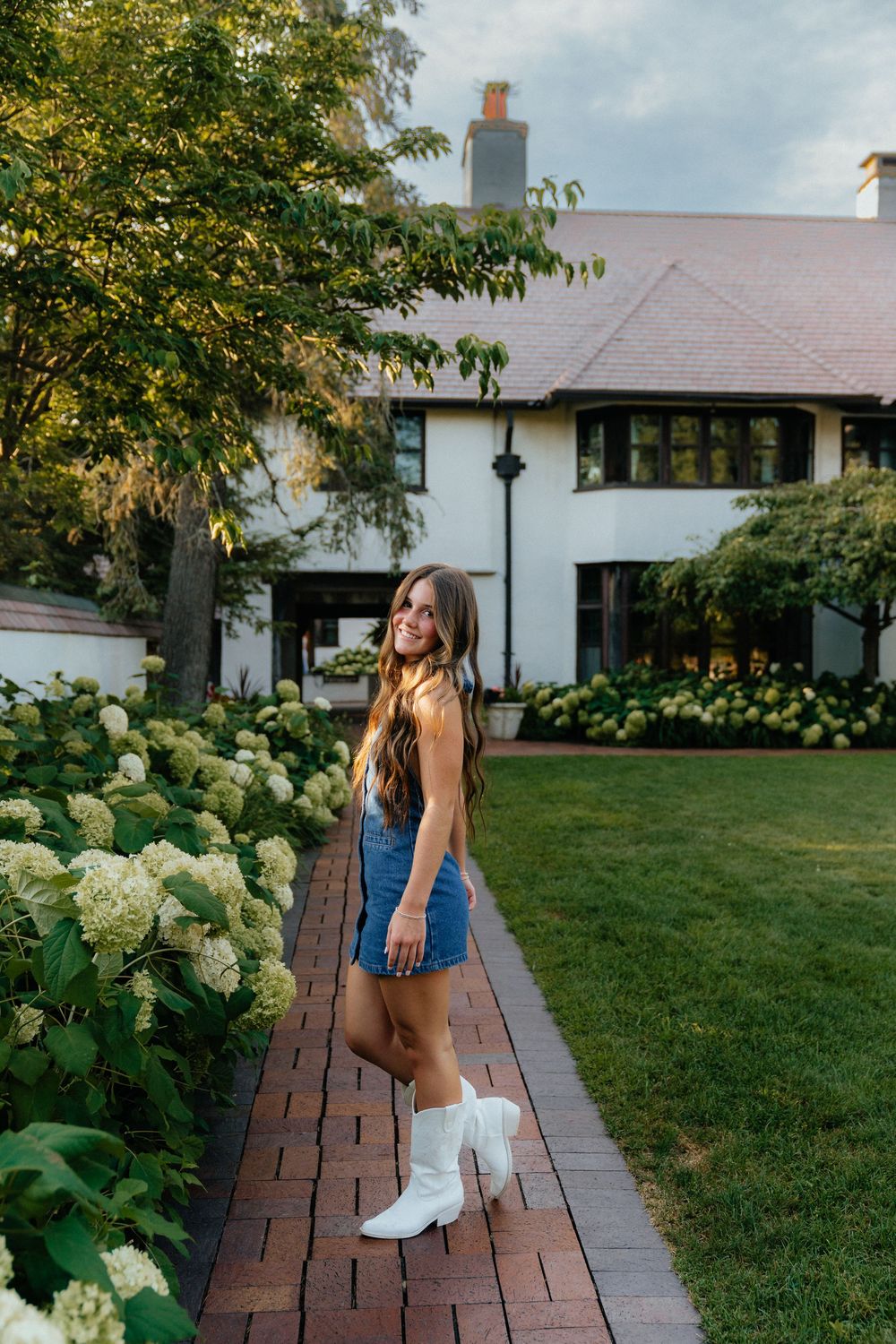 Person in casual outfit walking along wooden pathway beside blooming hydrangeas.