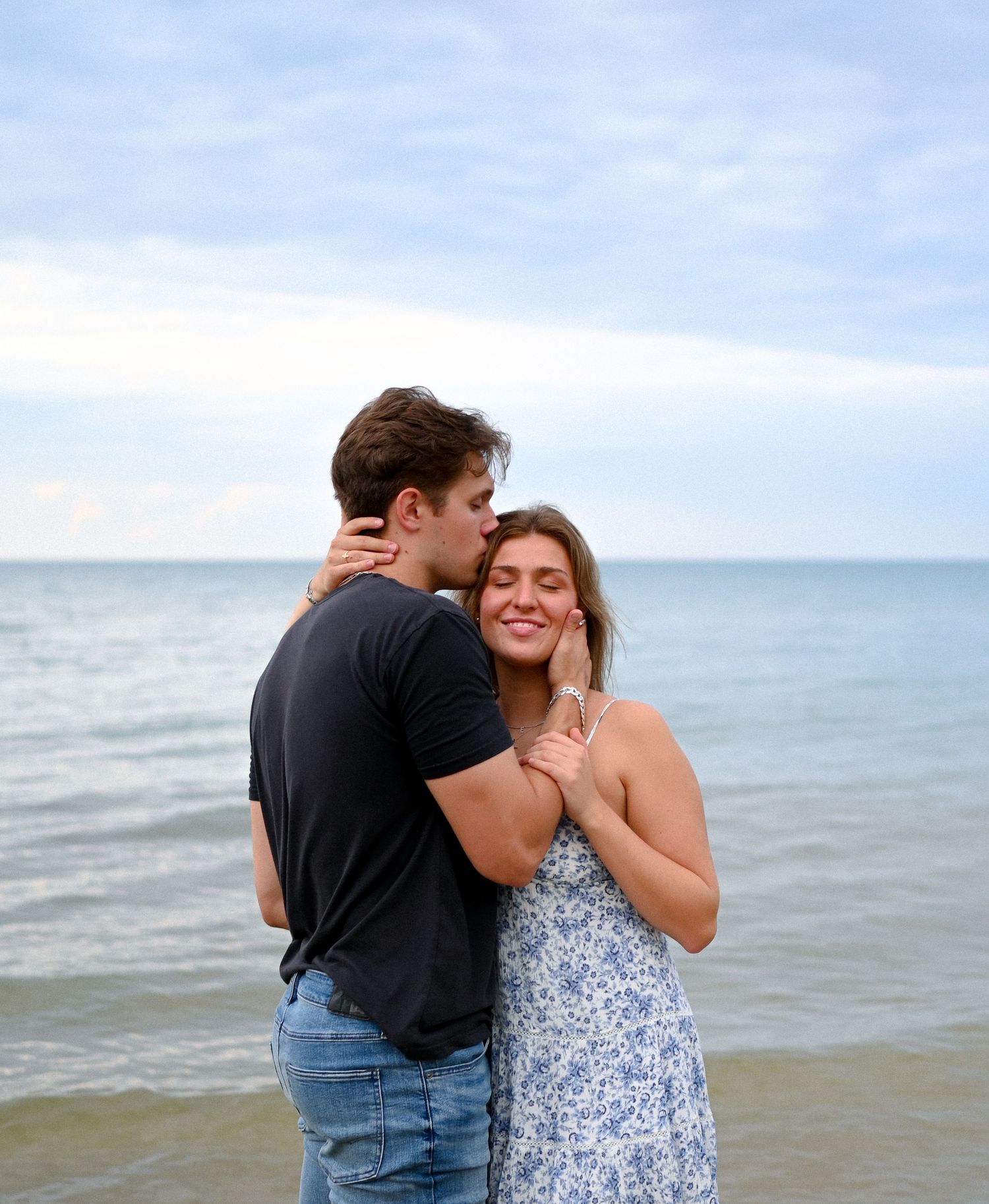 Couple sharing joyful moment together on beach with ocean backdrop.