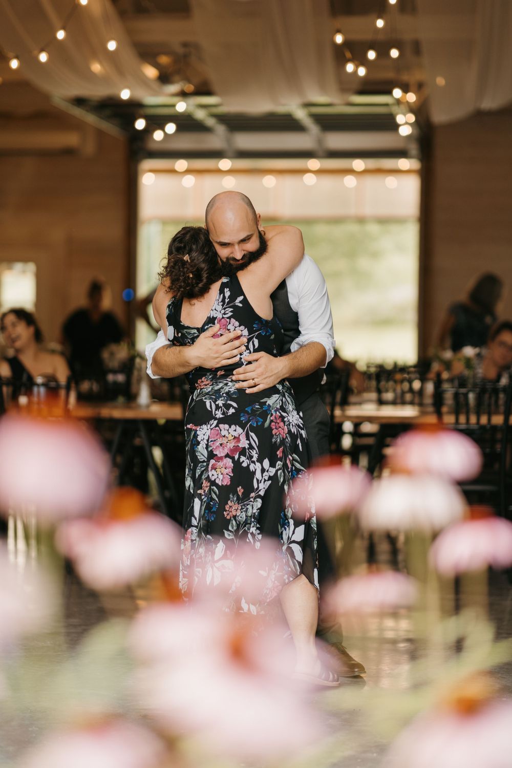 Groom embraces mother in a heartfelt hug during mother-son dance at rustic barn wedding reception.