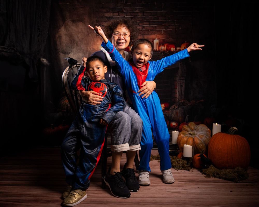 Group in superhero costumes striking dynamic poses against brick fireplace backdrop.