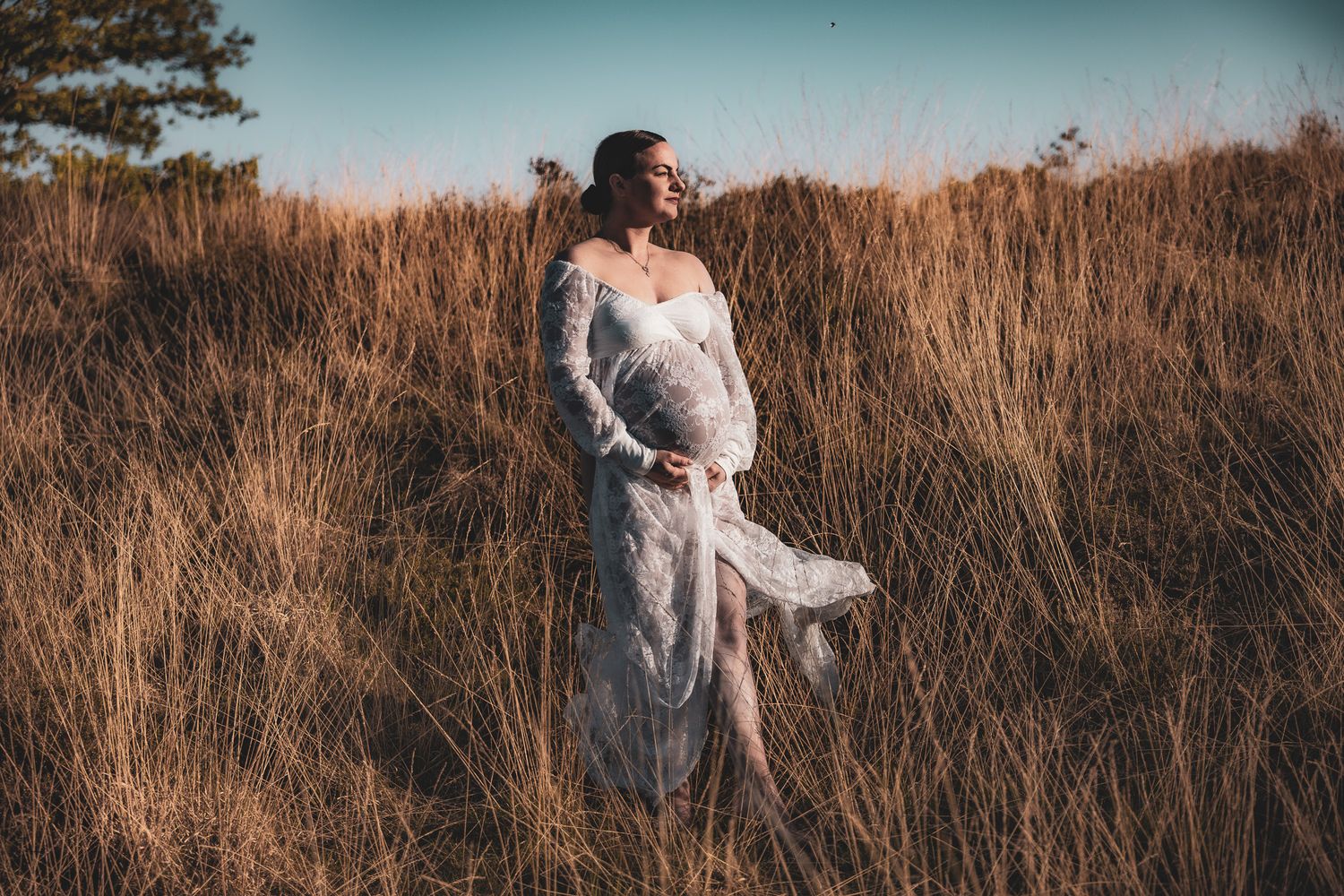 A moody maternity photo showing a couple embracing in a dark studio setting.