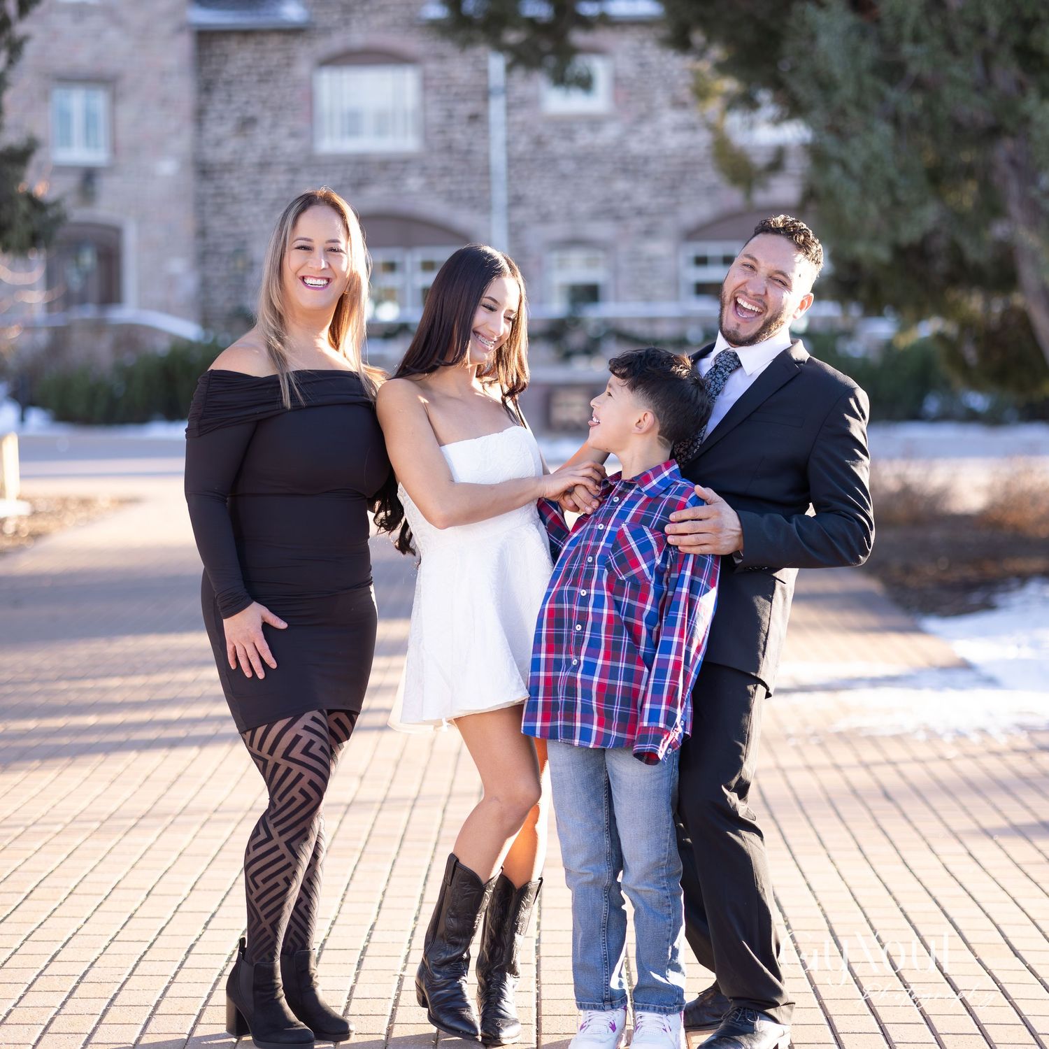 Stylish family group portrait on brick paved walkway in winter setting.