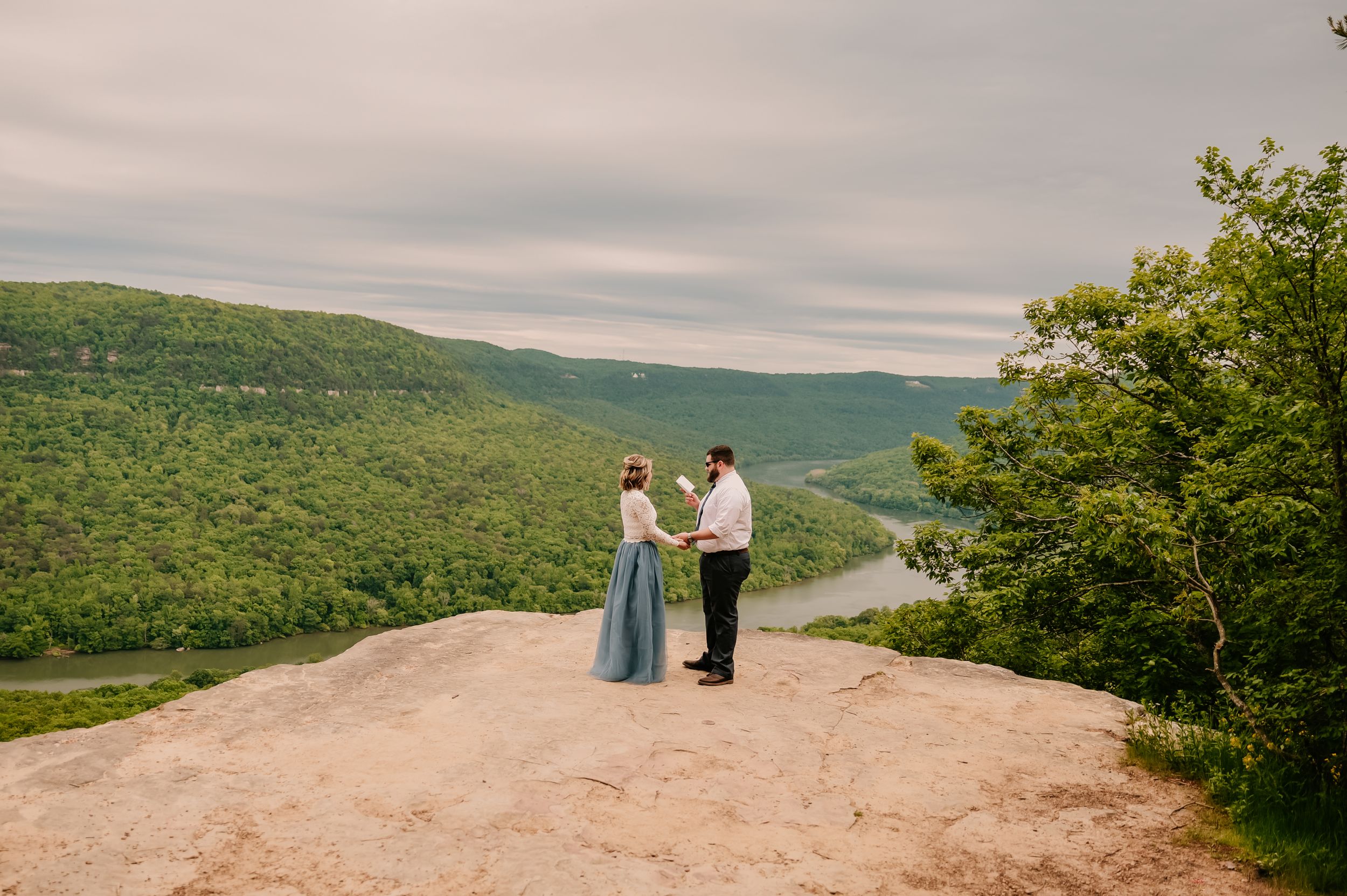 A romantic mountain-top moment captured against a backdrop of lush green hills.