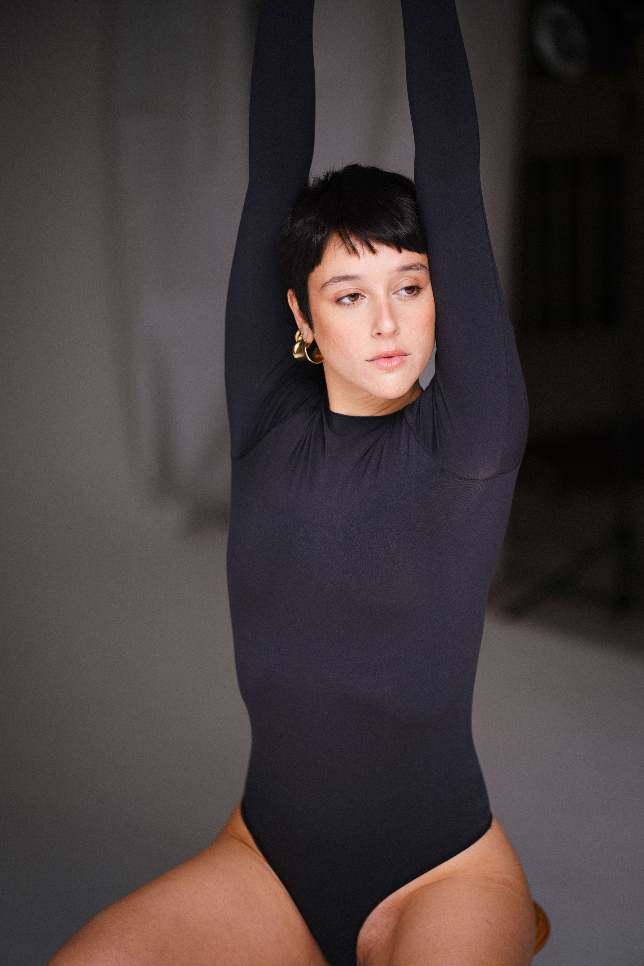 Studio portrait in black turtleneck against dark background with dramatic lighting.