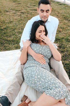 A couple having a romantic moment on a picnic blanket in a grassy field.