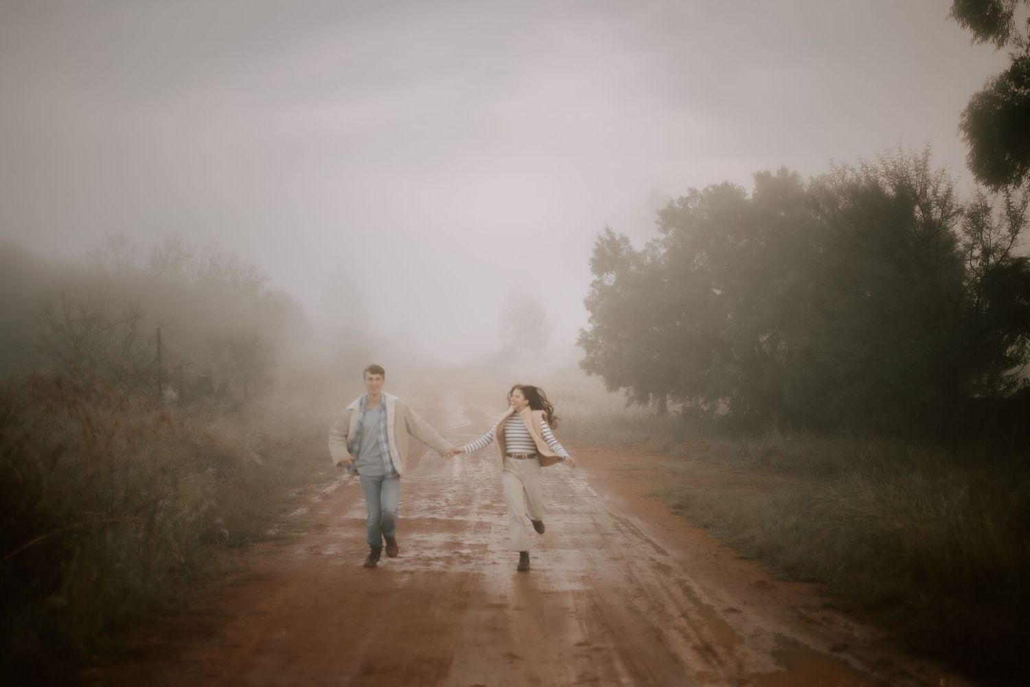 A dreamy scene of two people walking down a misty dirt road.