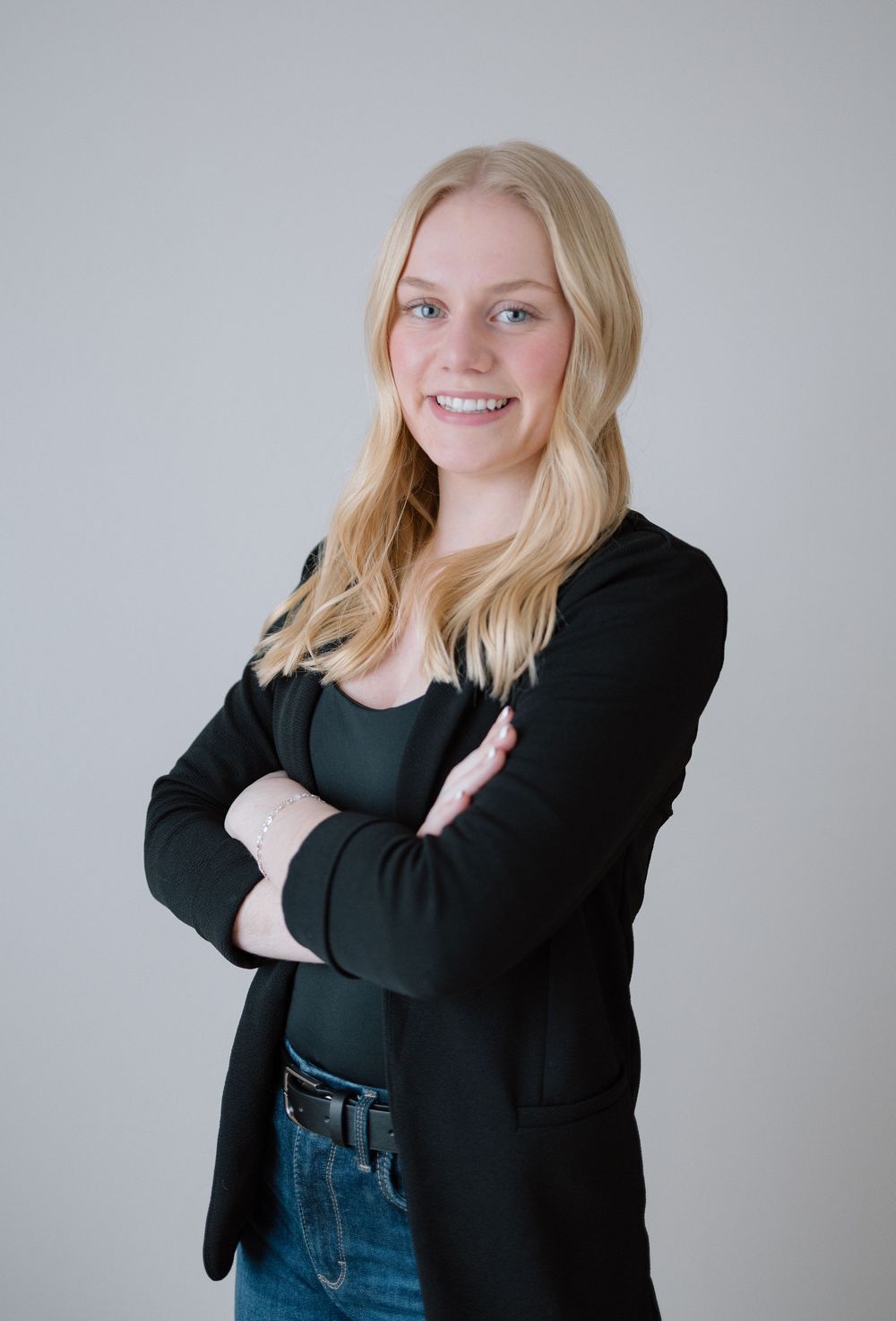 Professional headshots showing person in black blazer and jeans against grey background.