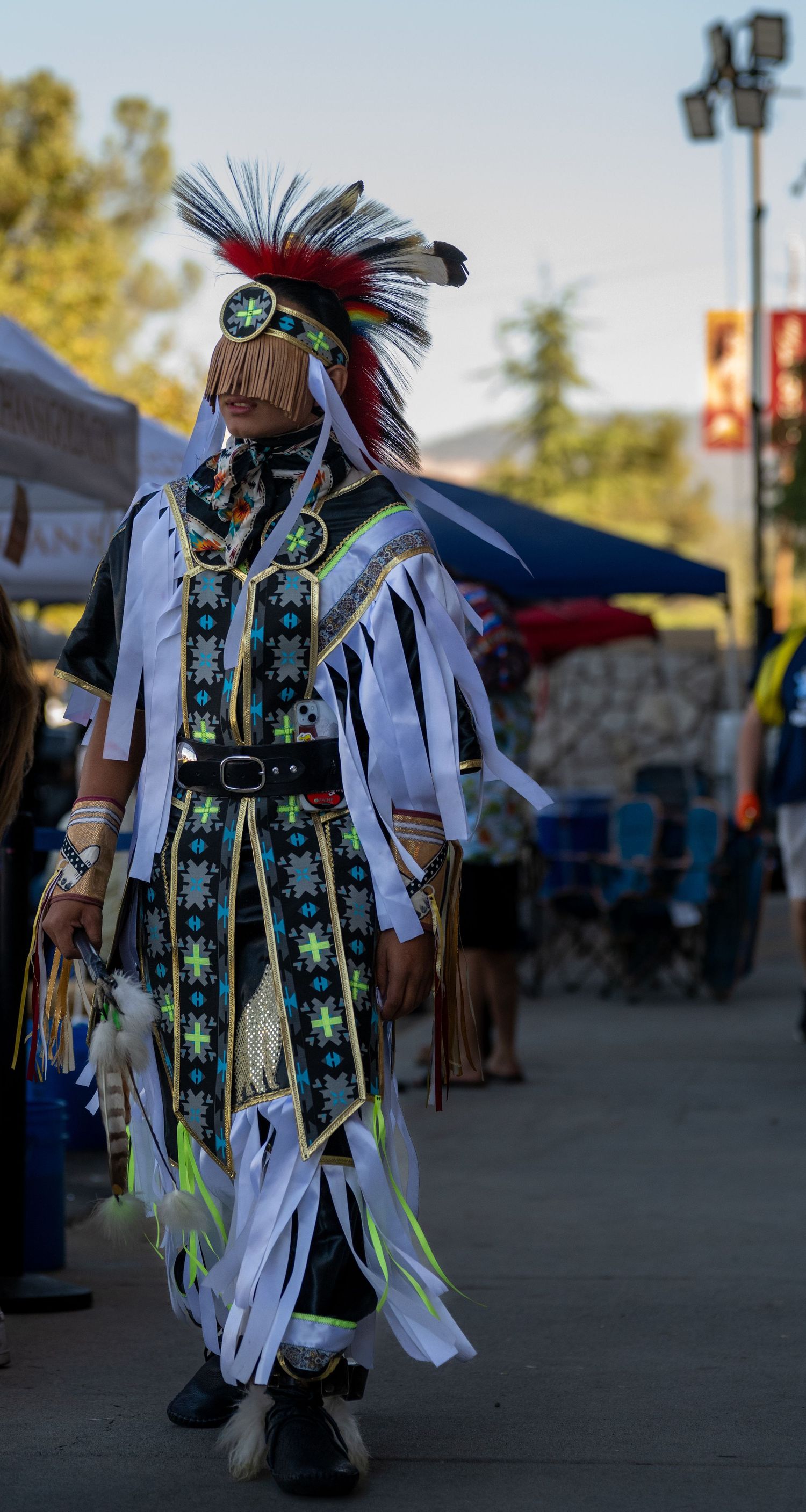 Traditional Native American dancers performing in colorful regalia at outdoor event.